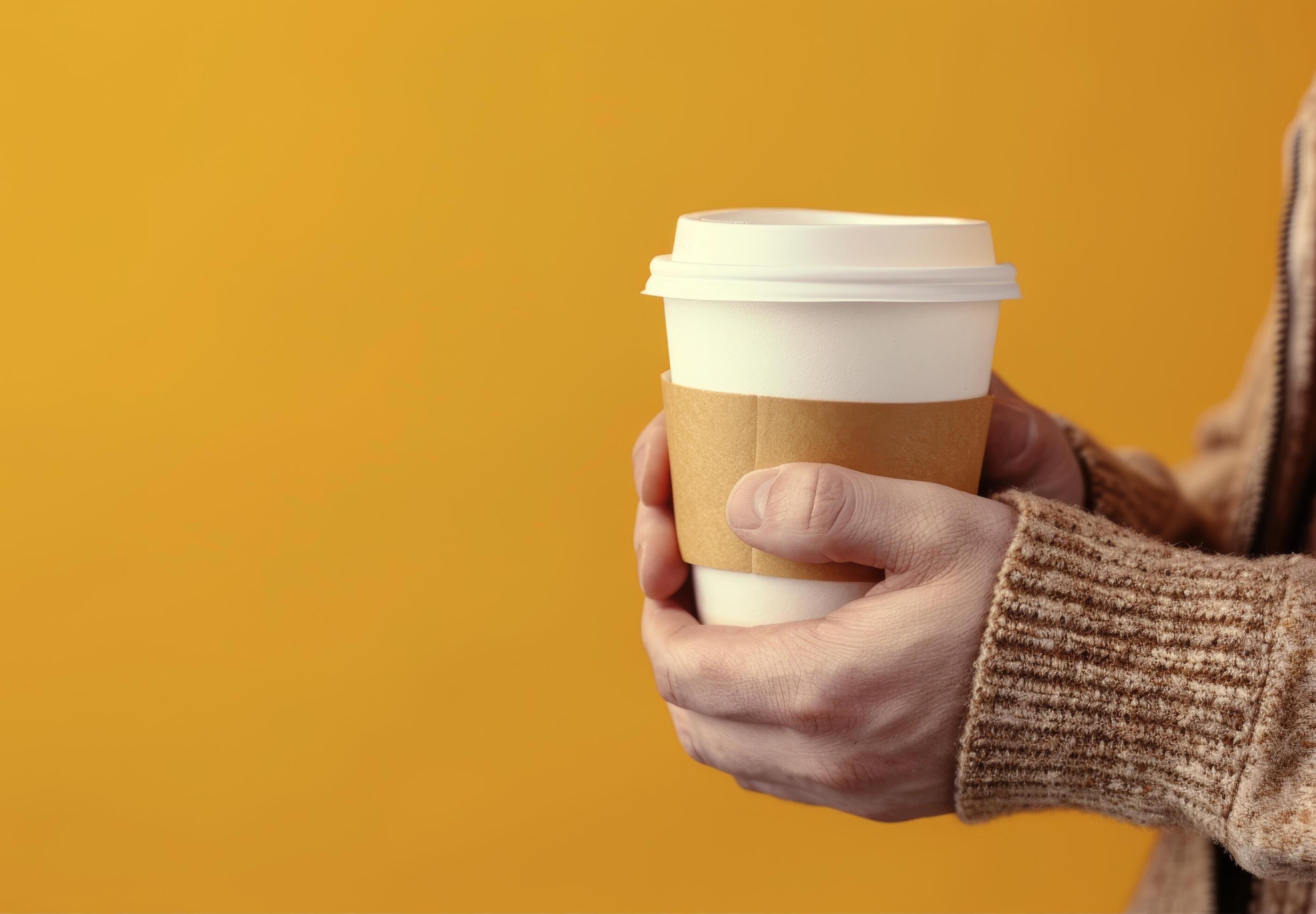 Warm Drink Held Against Yellow Background in Cozy Indoor Setting Stock Free