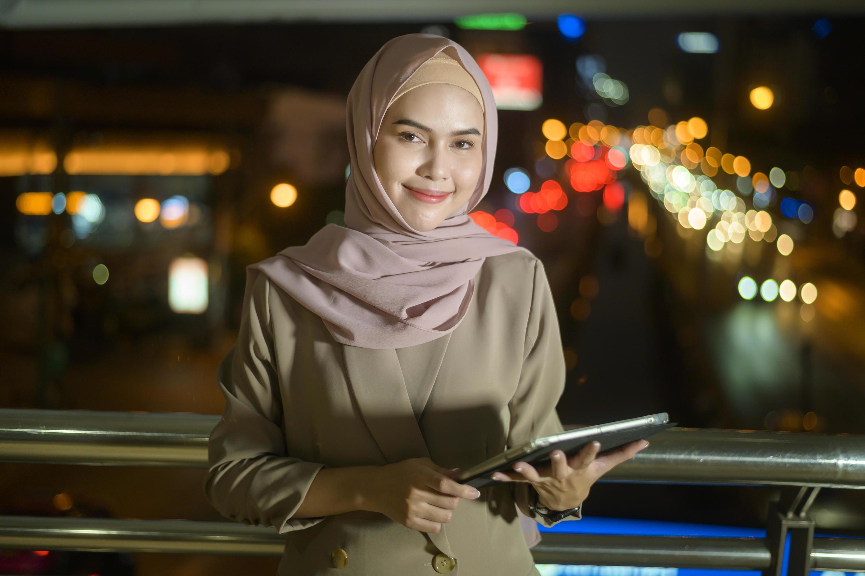 A young Muslim Businesswoman is using tablet computer in modern City at night , Business technology lifestyle concept Stock Free