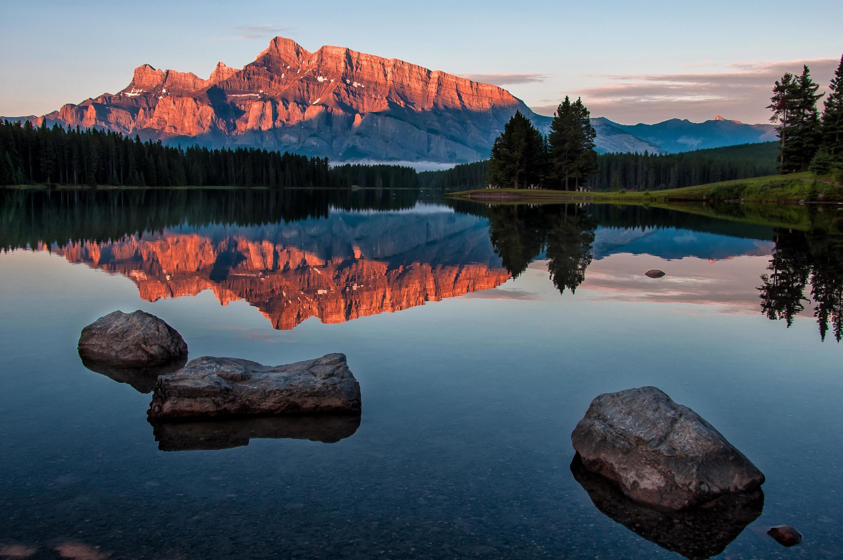 Rocks in water near mountain range at sunset Stock Free