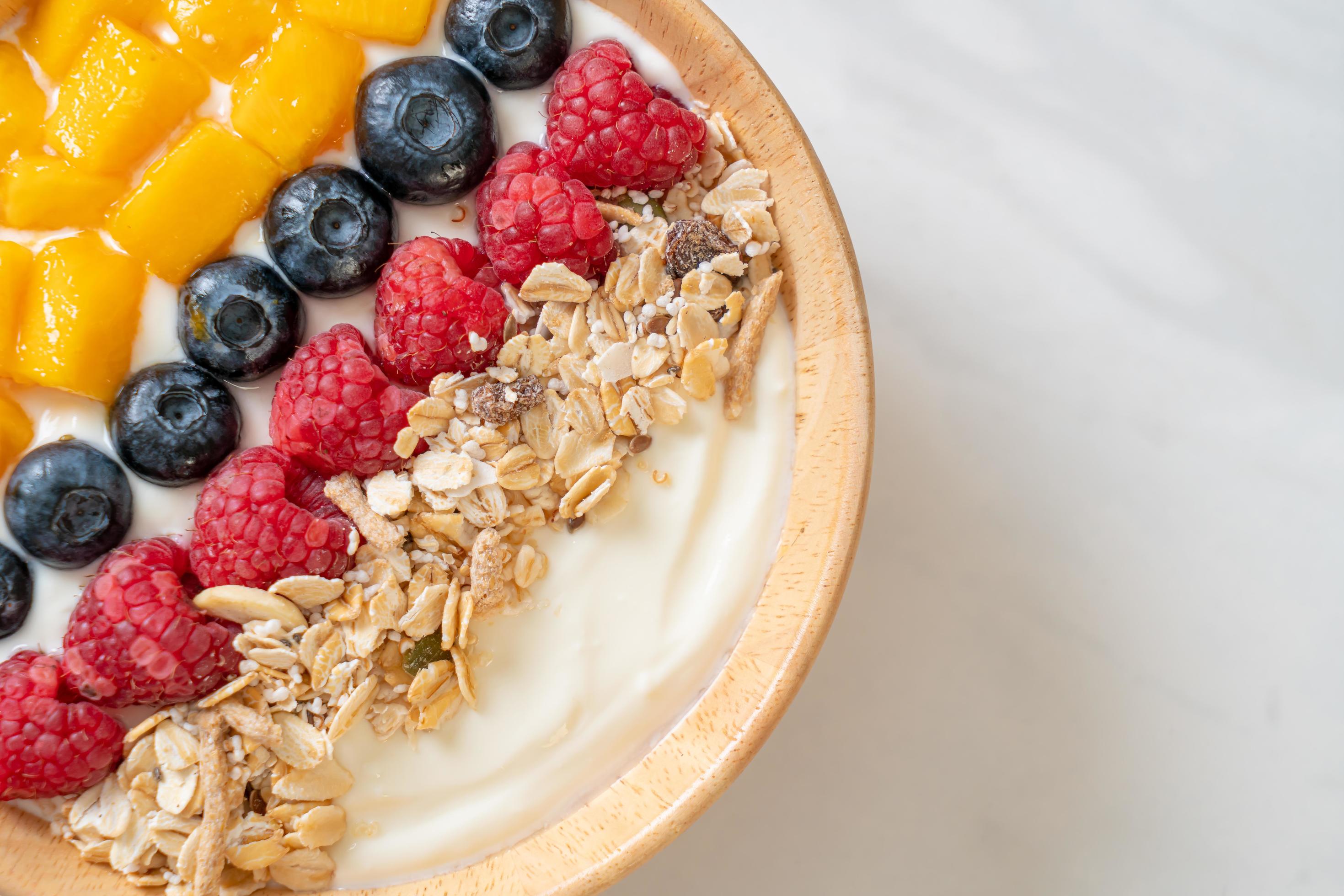 Homemade yogurt bowl with raspberry, blueberry, mango, and granola – healthy food style Stock Free