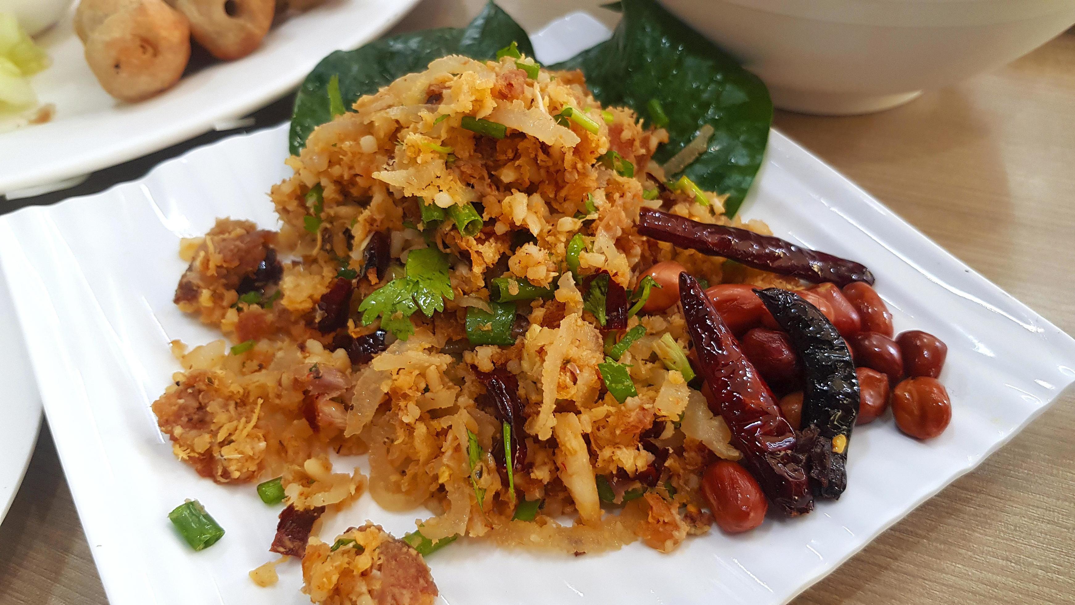 Spicy Salad of Curried Rice Croquettes Fermented Pork, Ginger, dry chili and Peanuts on white plate or dish at Thai restaurant. Asian food. Stock Free