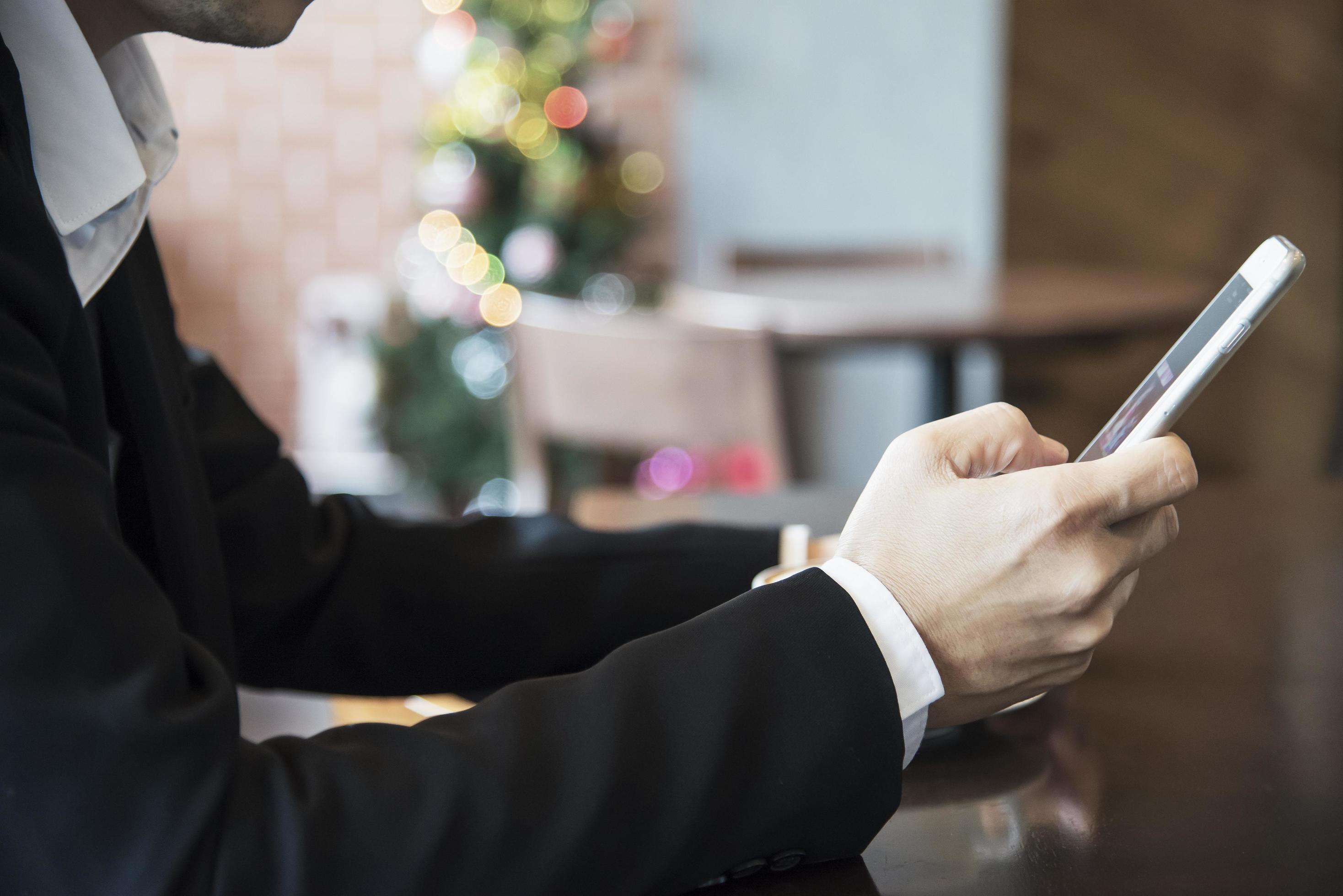 Business man using mobile phone while drinking coffee in coffee shop – modern life style business man in coffee shop concept Stock Free