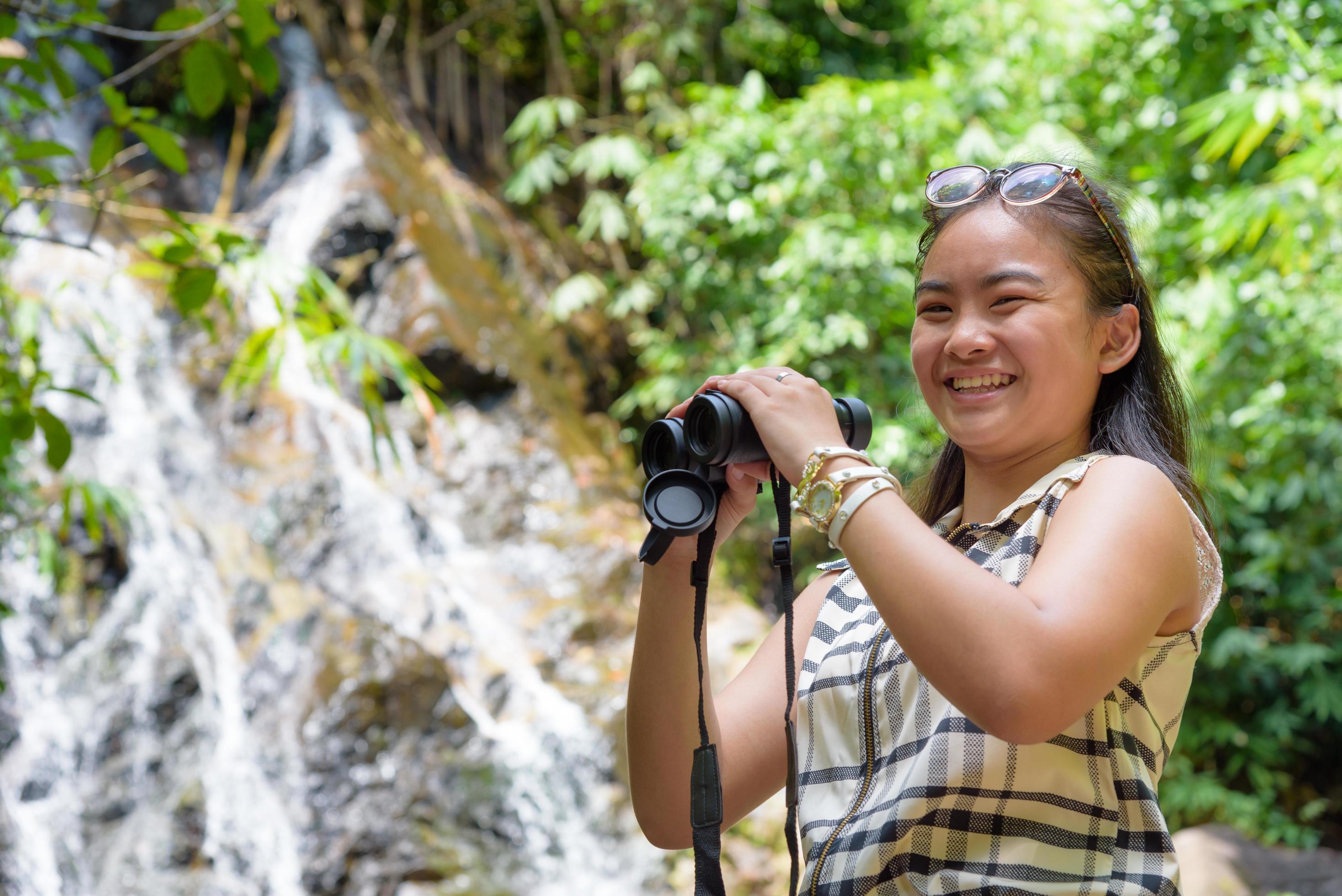 Girl using binoculars in forest Stock Free