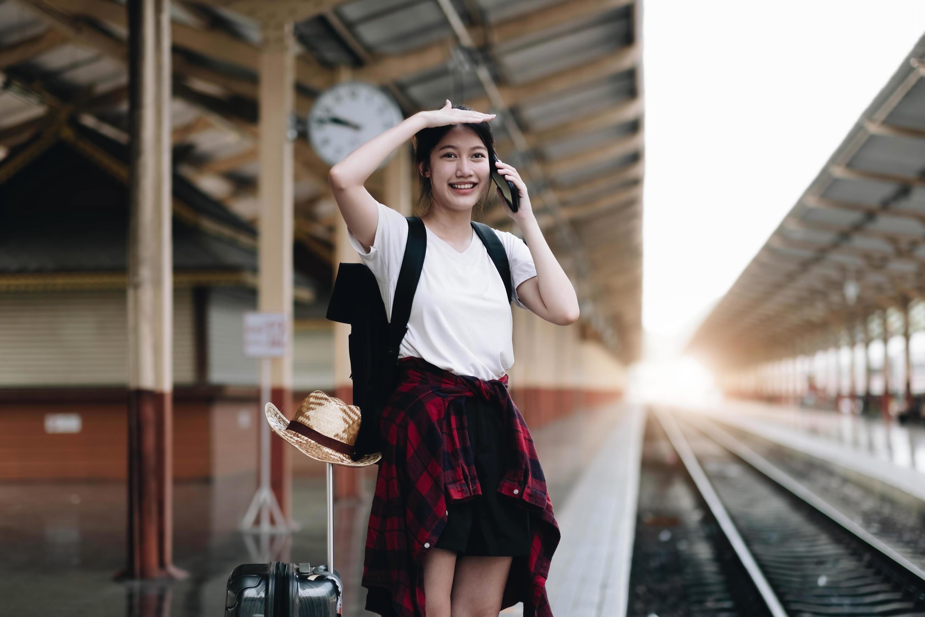 Young traveler woman looking for friend planning trip at train station. Summer and travel lifestyle concept Stock Free