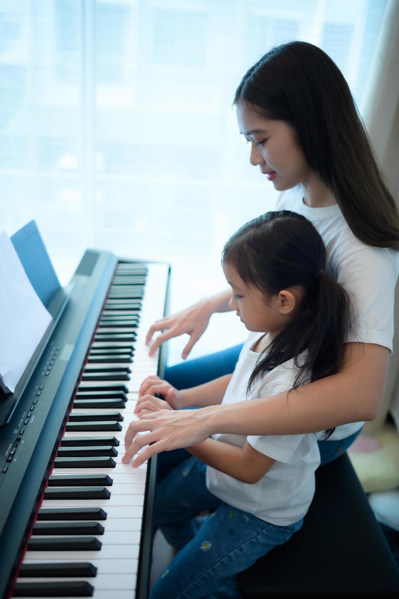 Family vacation, other helping daughter practice in her piano lessons Stock Free