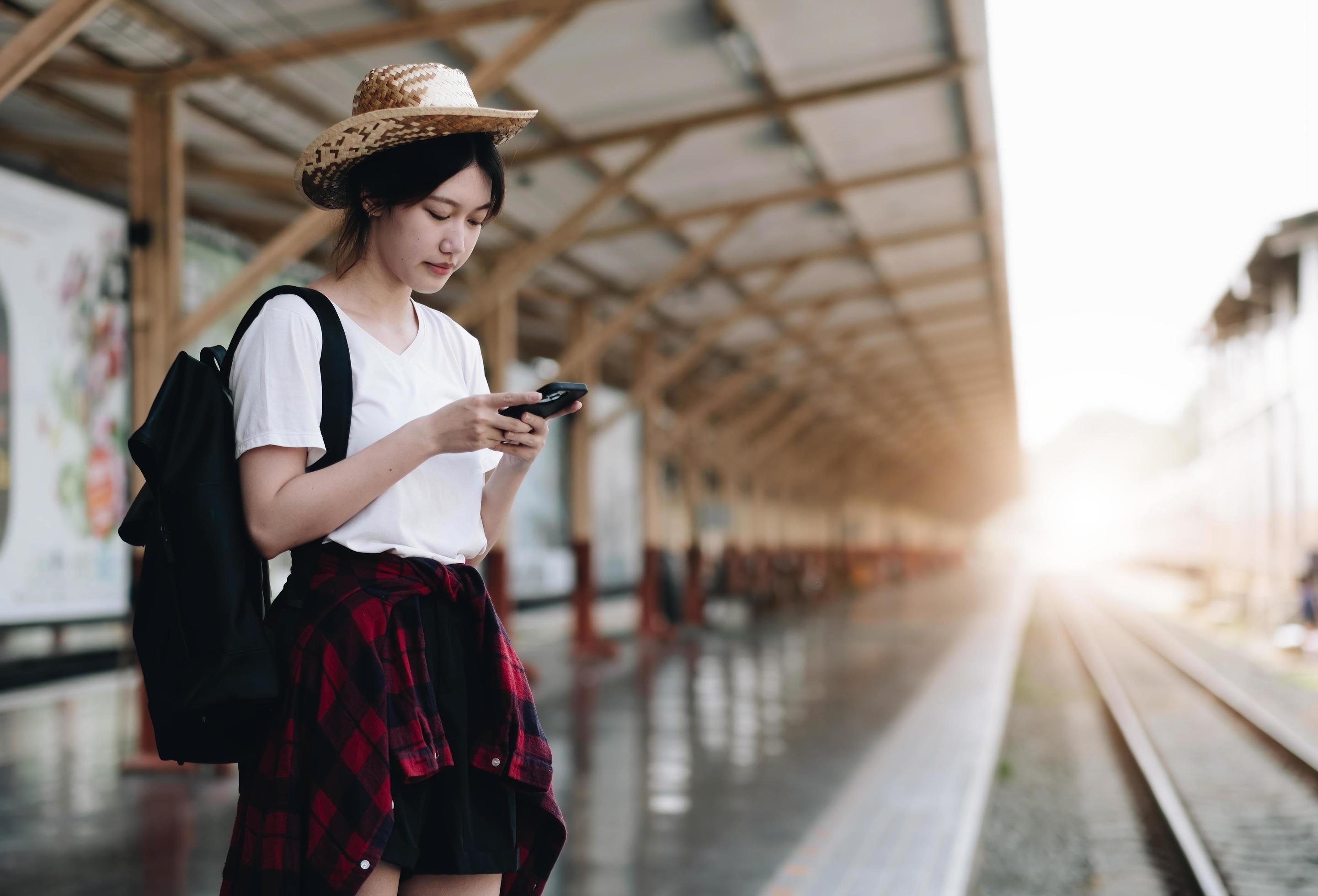 Young traveler woman looking for friend planning trip at train station. Summer and travel lifestyle concept Stock Free