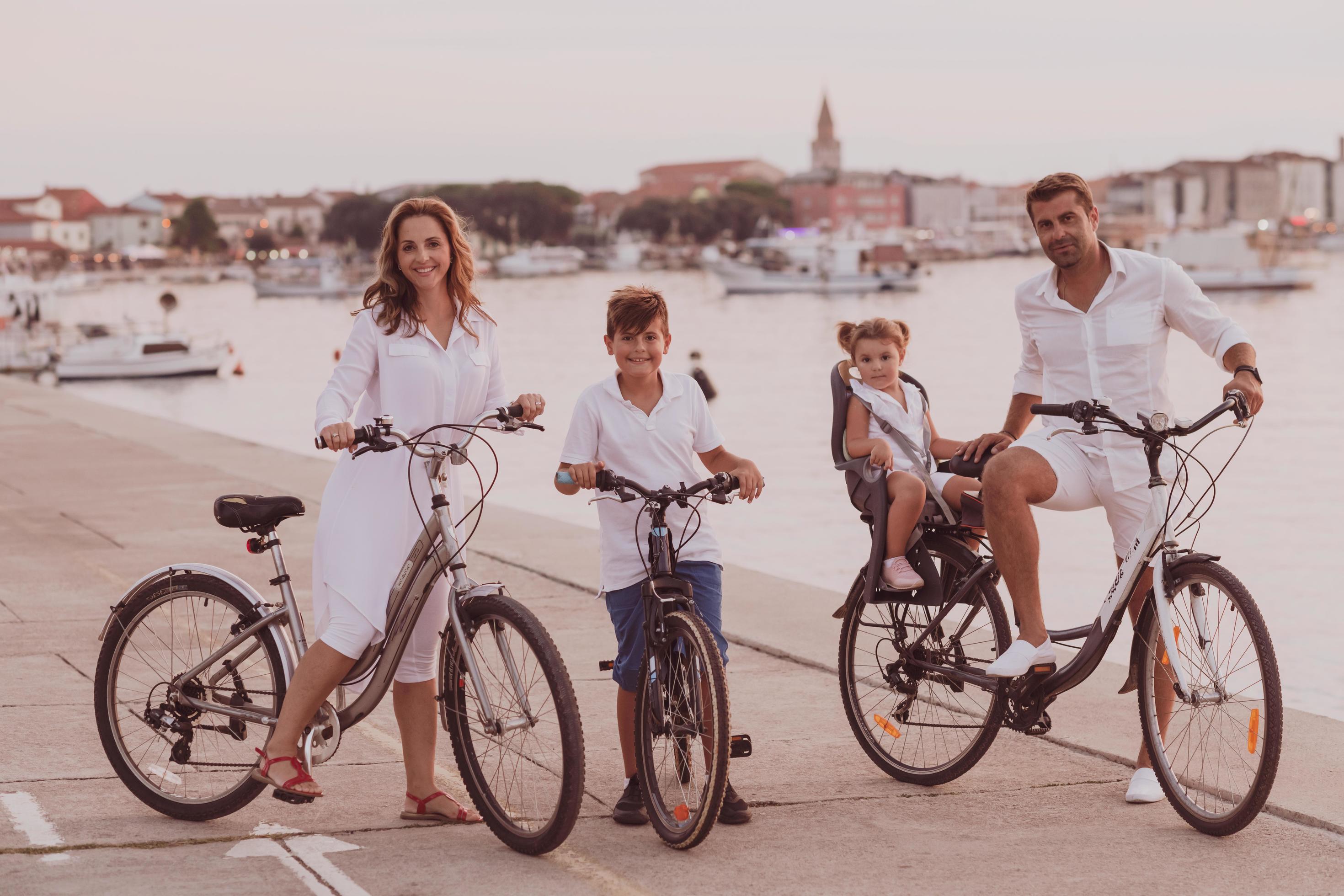 The happy family enjoys a beautiful morning by the sea riding a bike together and spending time together. The concept of a happy family Stock Free