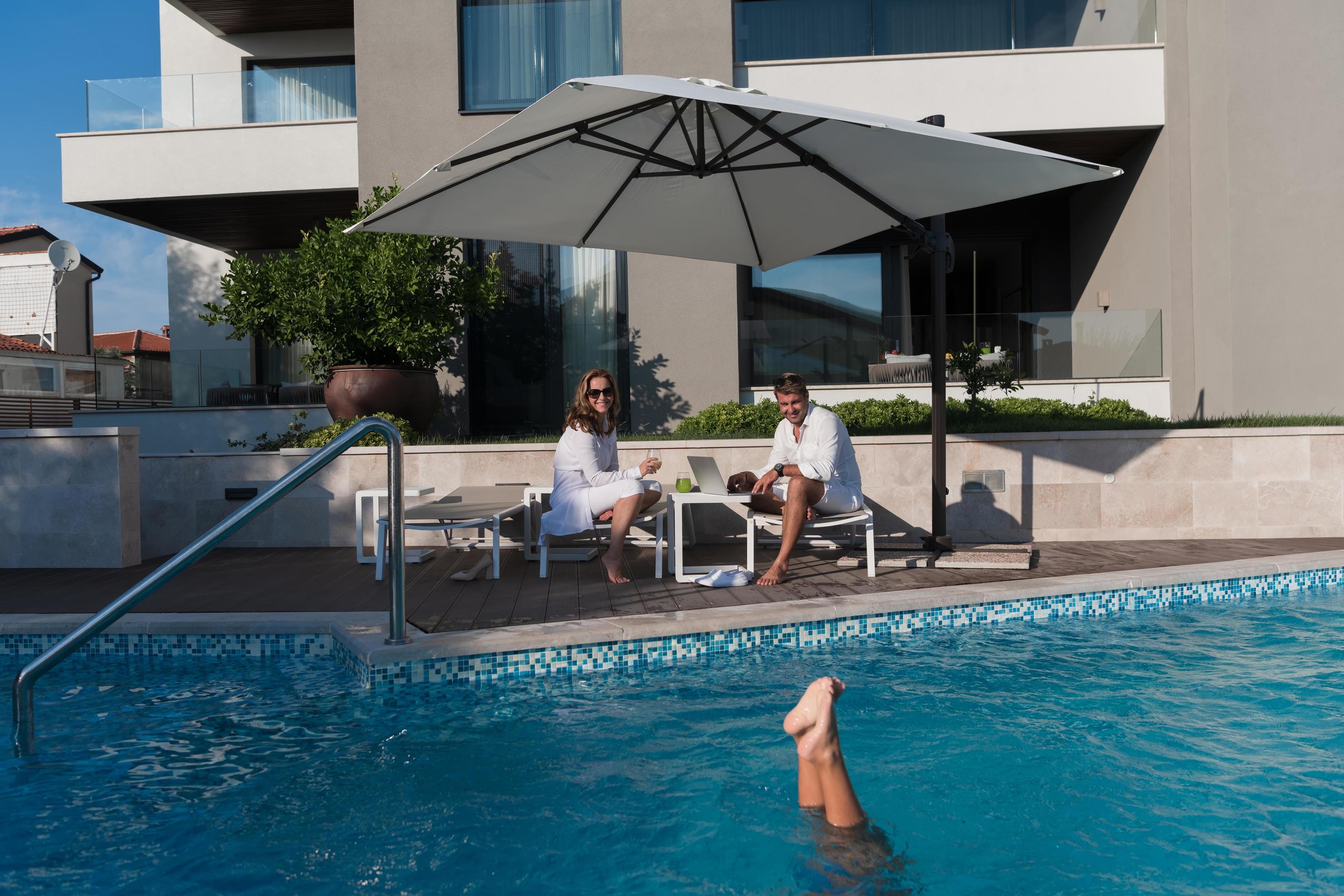 Happy family enjoys vacation in a luxury house with pool. Senior couple spends time with their son during the vacation. Selective focus Stock Free