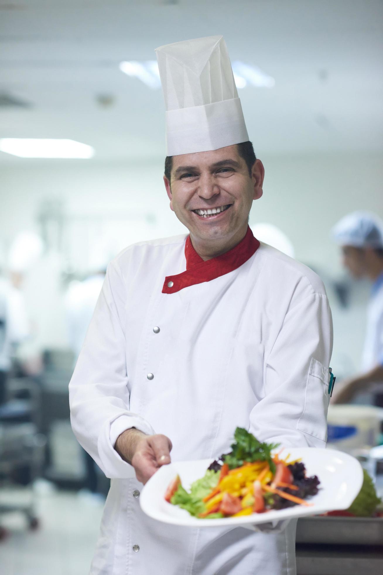 chef in hotel kitchen preparing and decorating food Stock Free