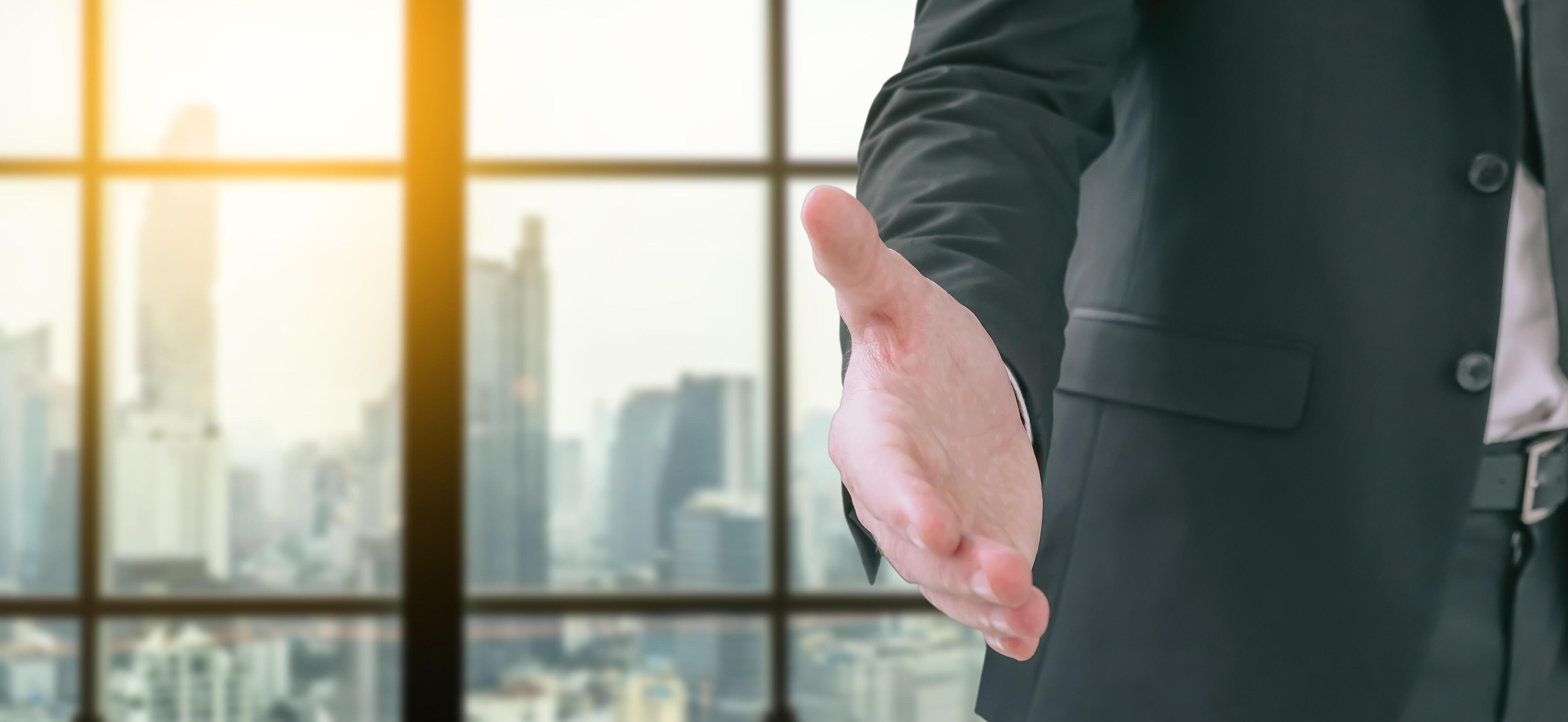 Business man is standing and open hand ready to seal a deal with city scape in background, partner shaking hands, shaking hands, copy space Stock Free