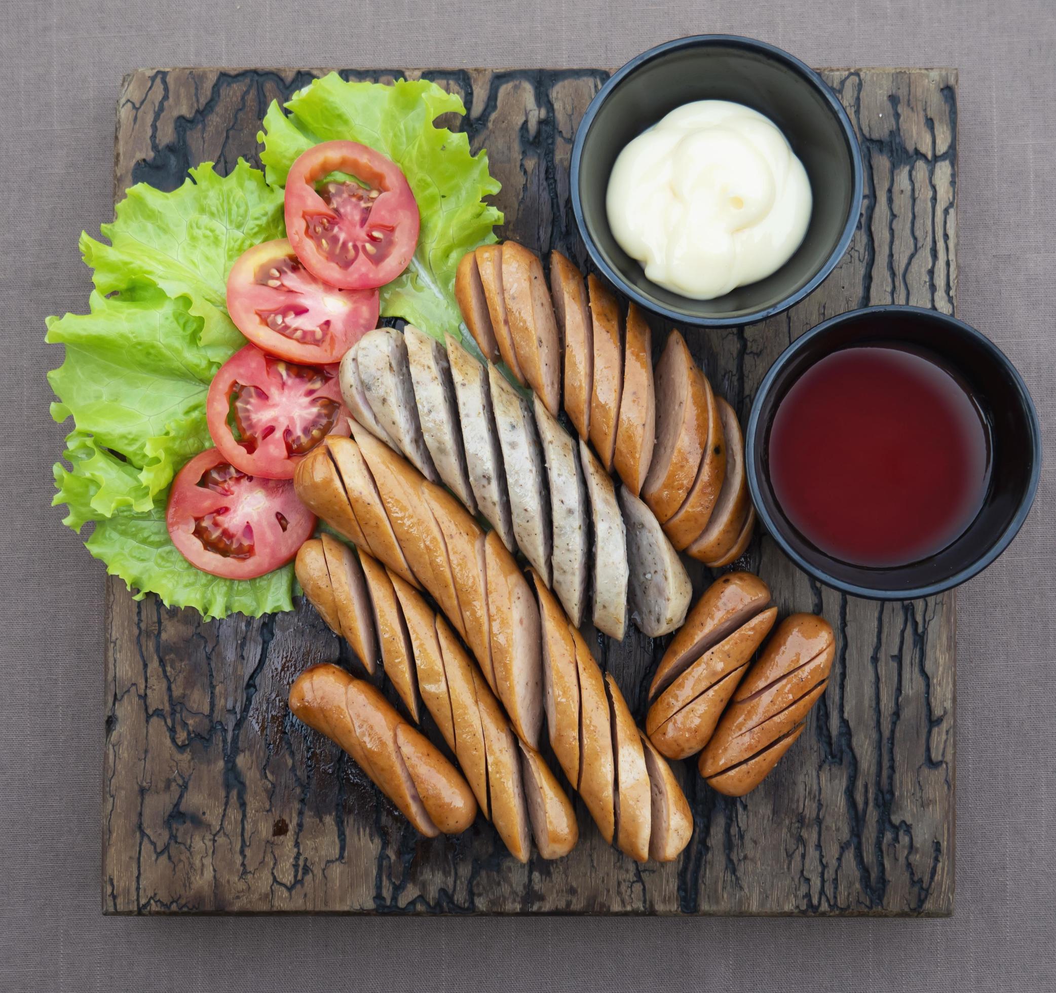 Fried sausages recipe with fresh tomato and sauces ketchup ready to be served, international food style concept Stock Free