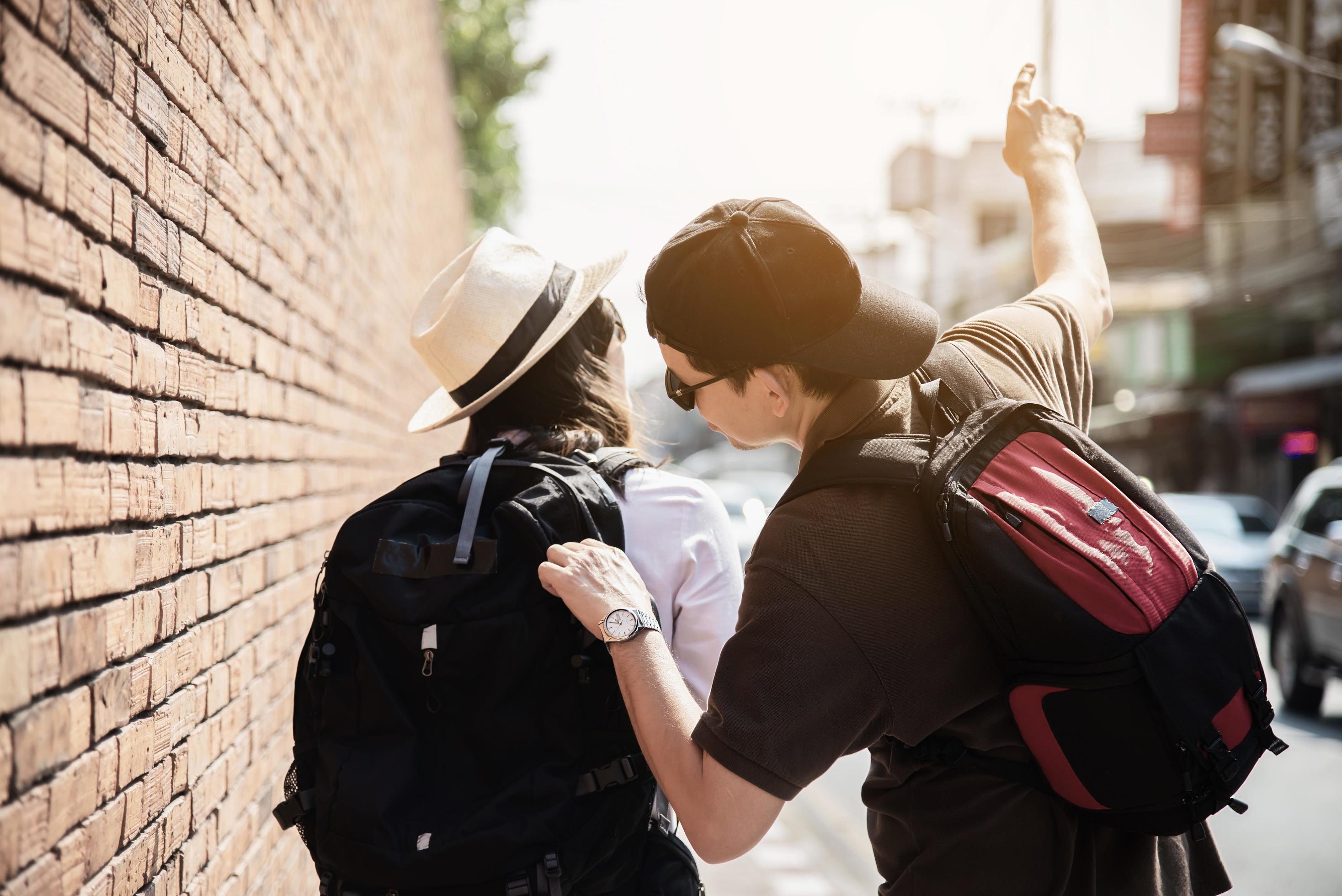 Asian backpack couple tourist holding city map crossing the road – travel people vacation lifestyle concept Stock Free