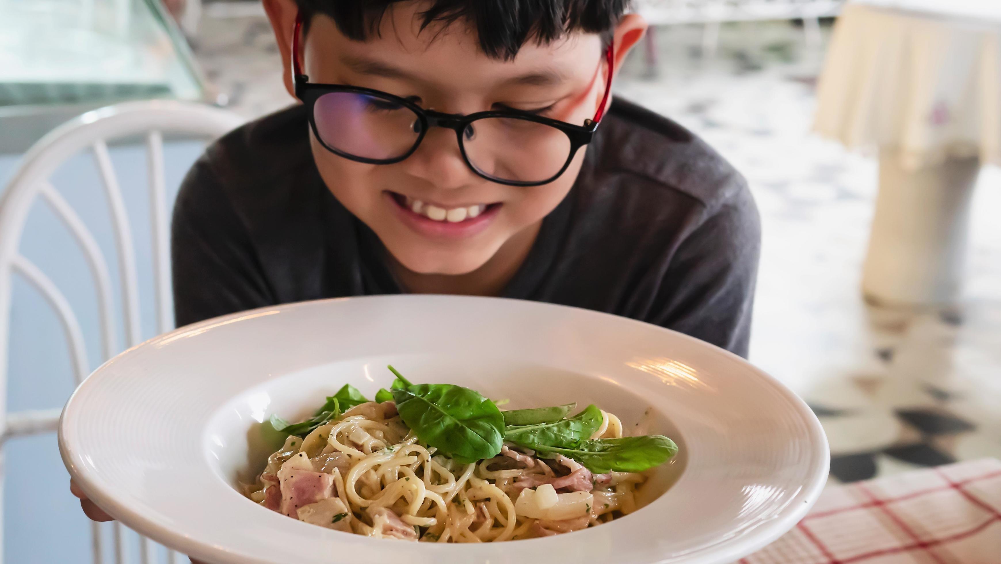 Boy happy eating spaghetti carbonara recipe – people enjoy with famous Italian dish food concept Stock Free