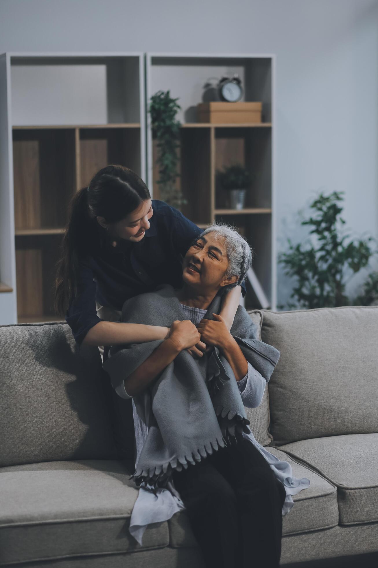 happy family Granddaughter takes care of her grandmother with warm cloths sitting on the sofa. Stock Free