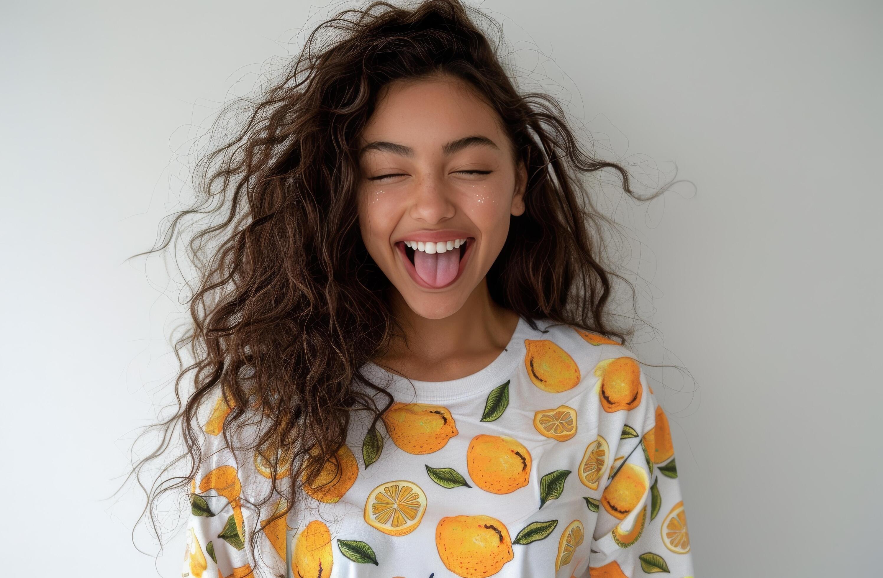 Young Woman With Curly Hair Smiles and Sticks Out Tongue Stock Free