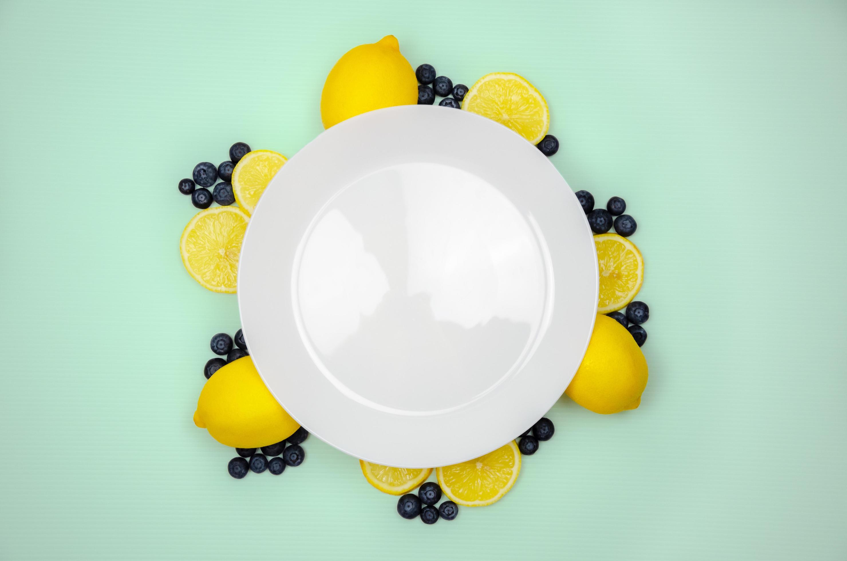 Fresh blueberries and lemon on top view with white plate and pastel green color background for healthy food concept. Stock Free