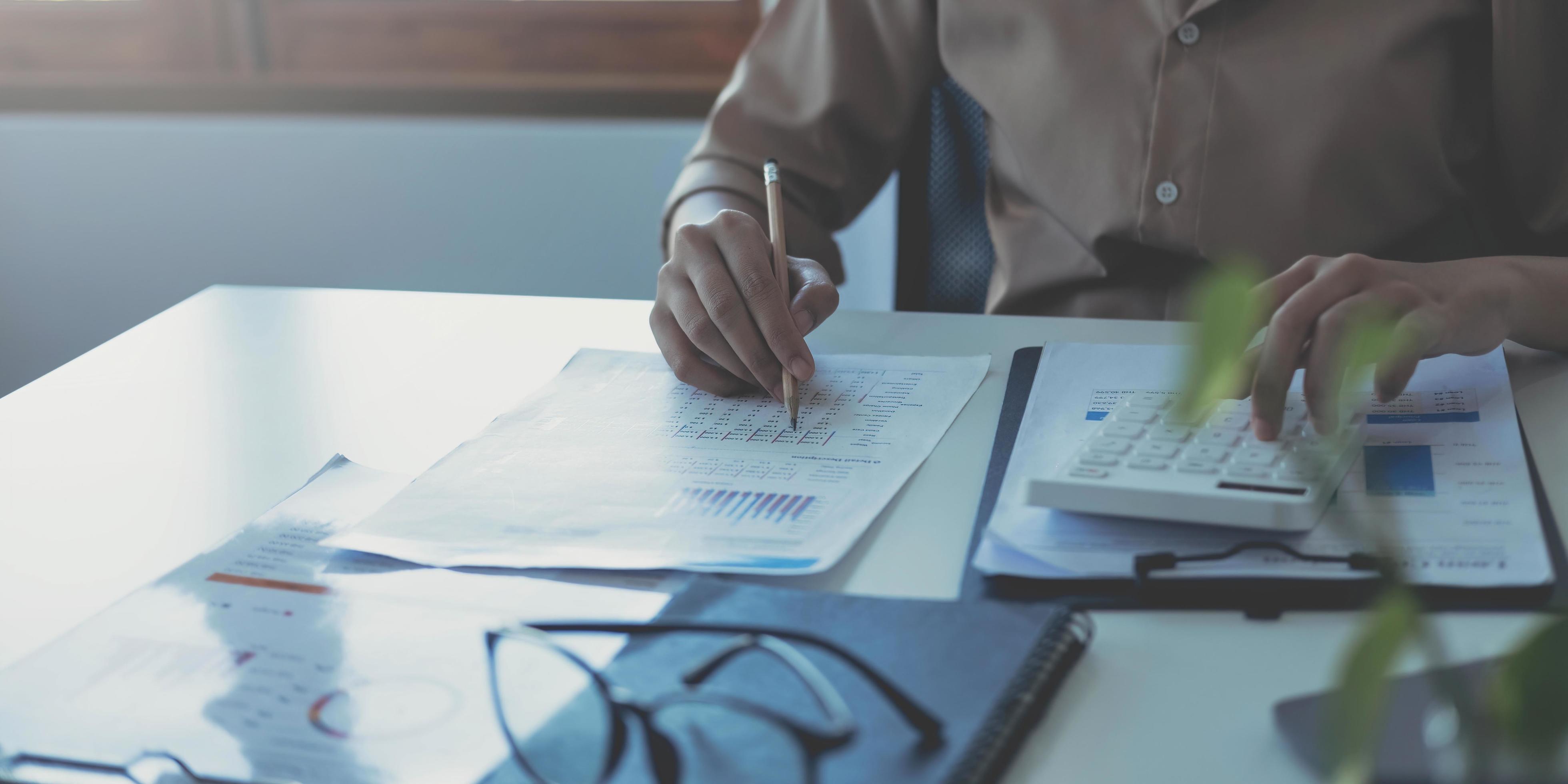 Business woman using calculator and writing make note with calculate. Woman working at office with laptop and documents on his desk Stock Free