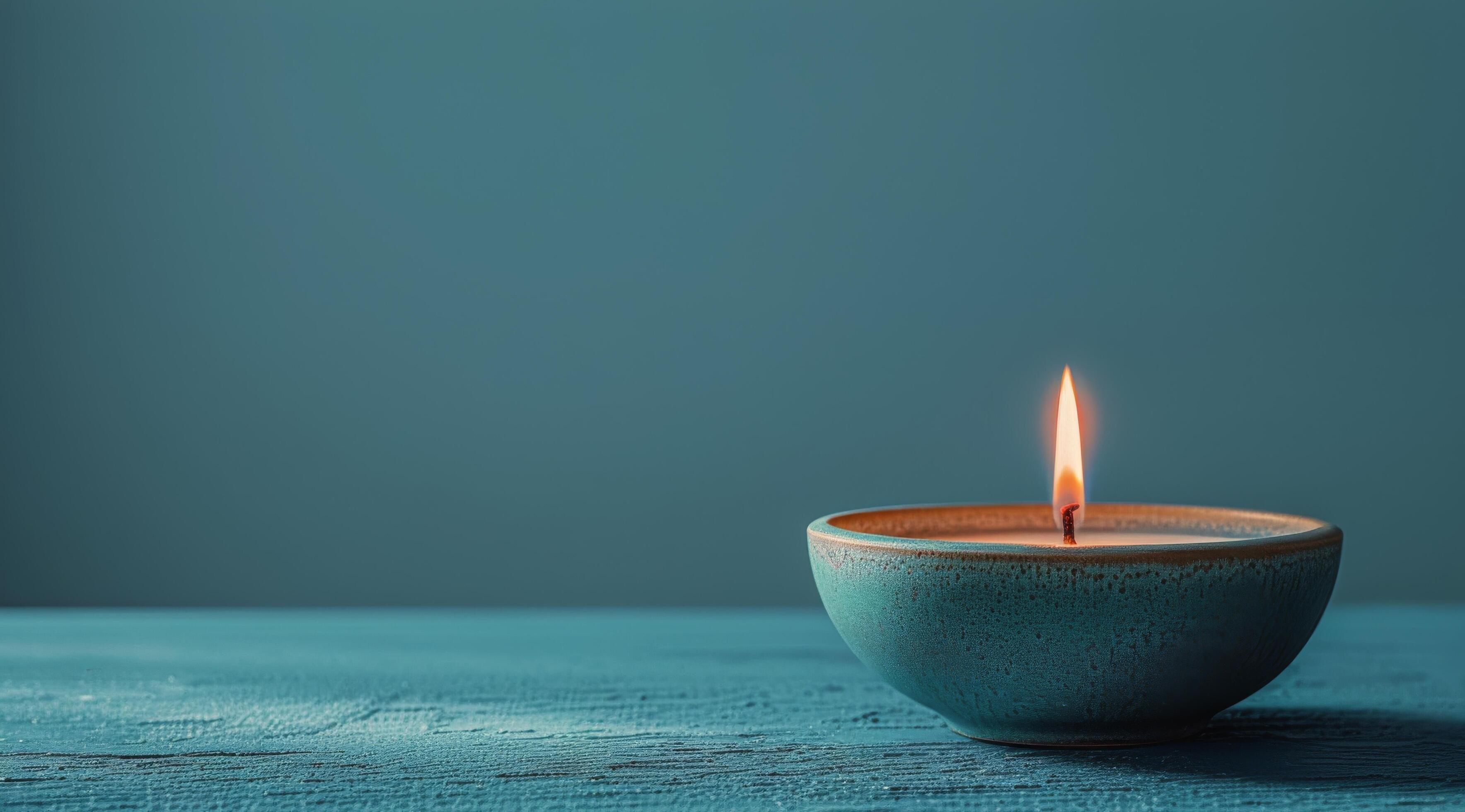 Single Teal Candle Burning on Blue Wooden Table Stock Free