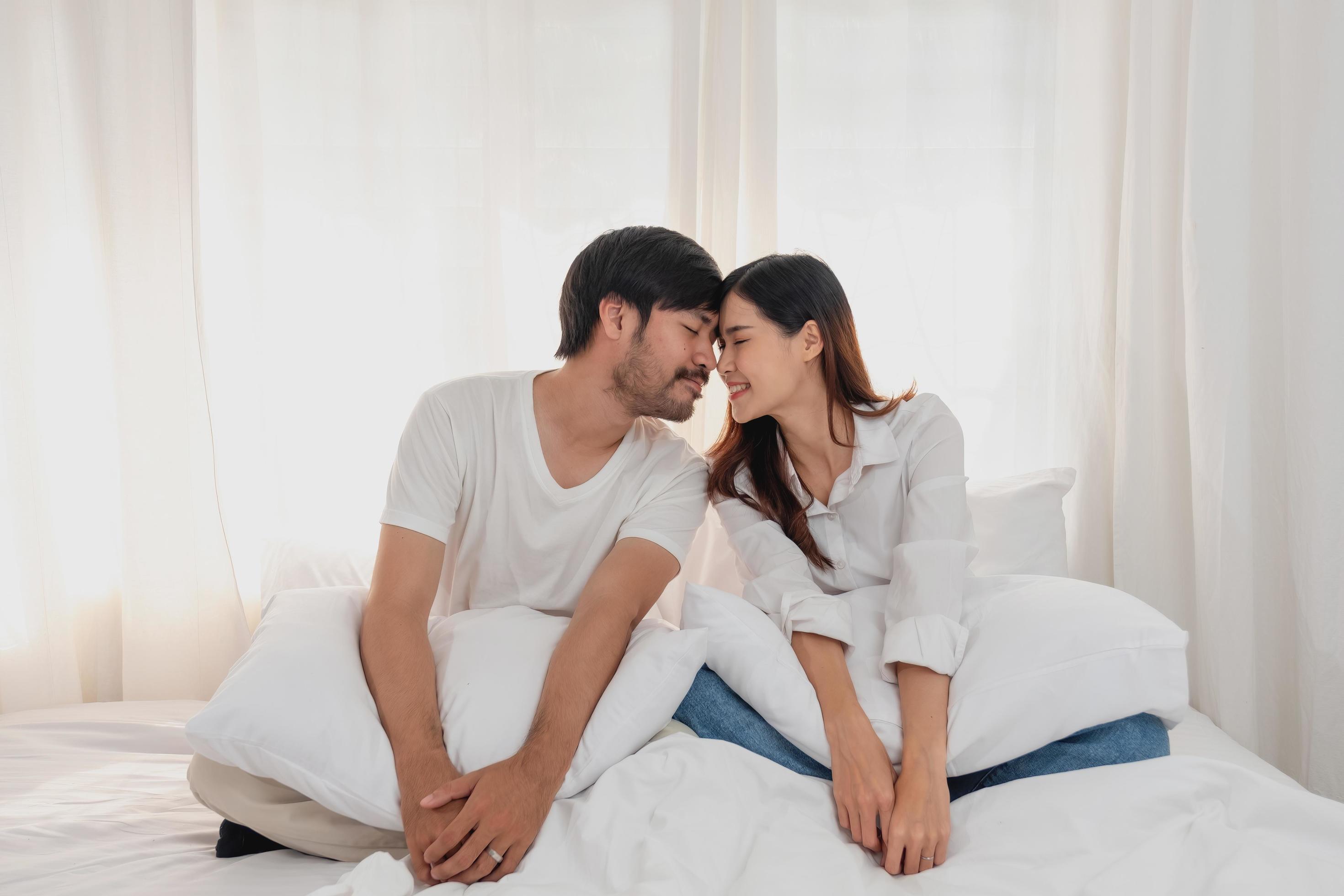 Happy young asian couple embracing, teasing, playing cheerfully in bed at home, romantic time to enhance family bonding. family concept. Stock Free