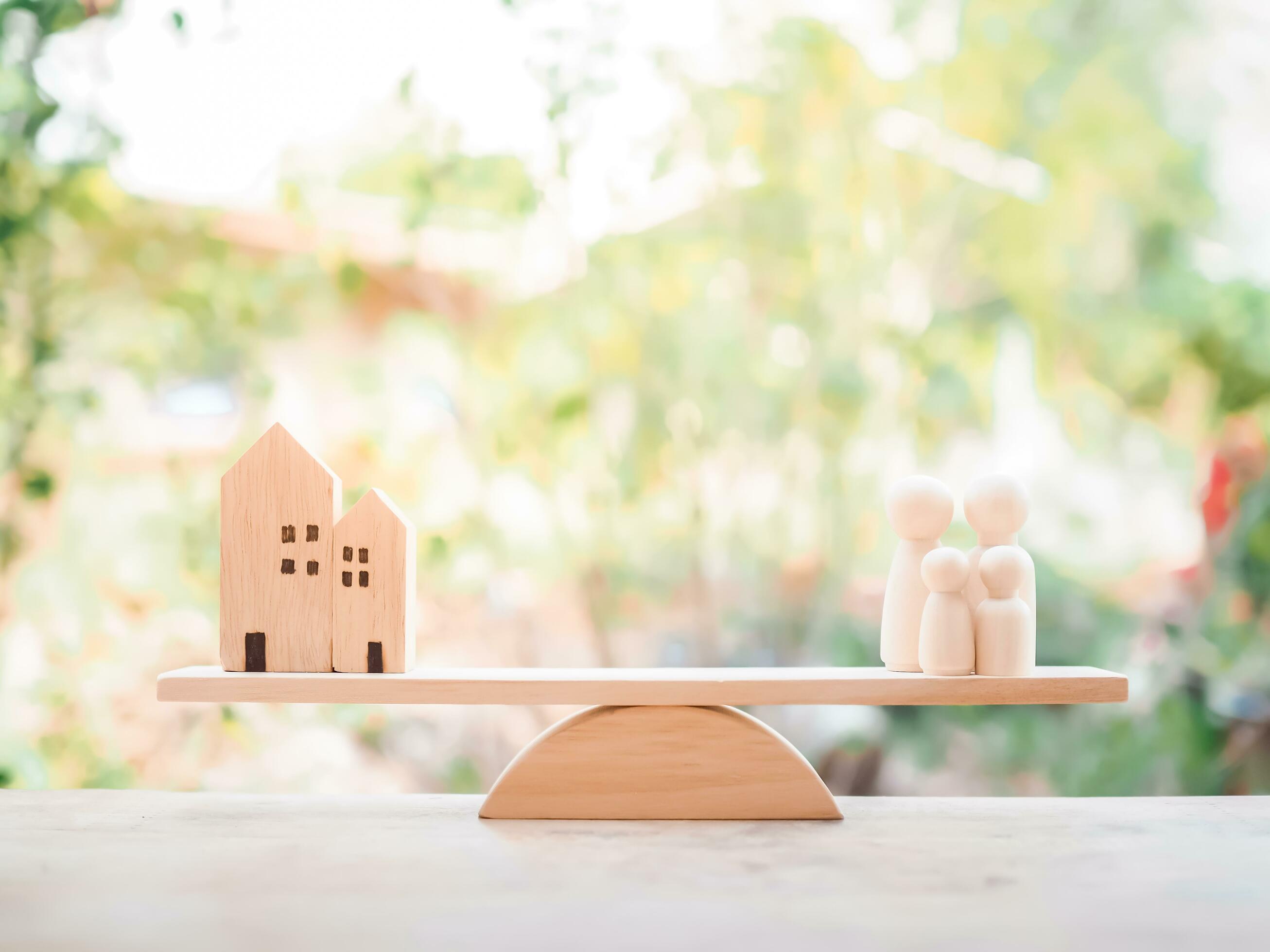 Miniature house and wooden human figure on balancing scale for family concept Stock Free