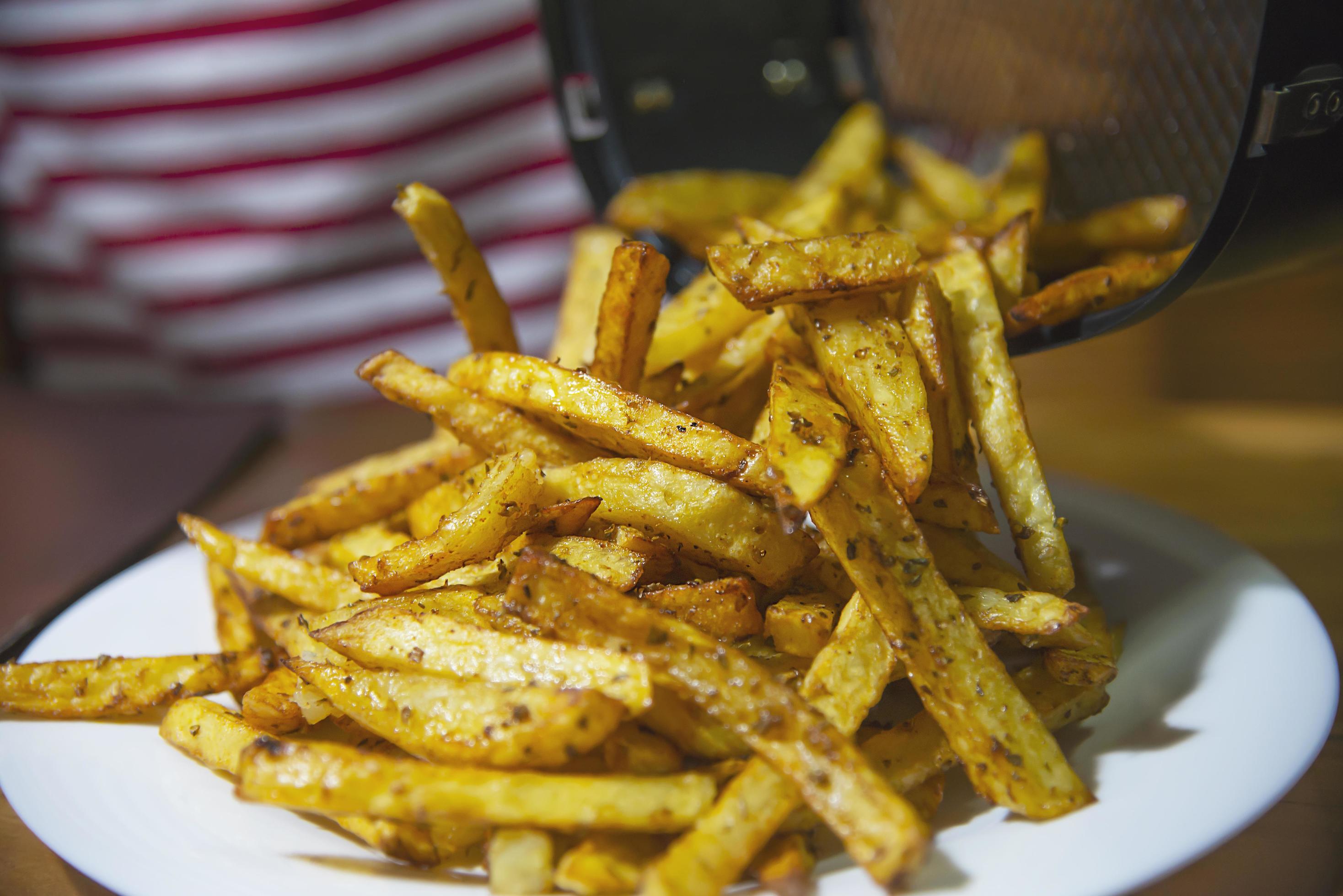 Delicious French fried potato mix with chilly powder on wooden table – traditional fast food concept Stock Free