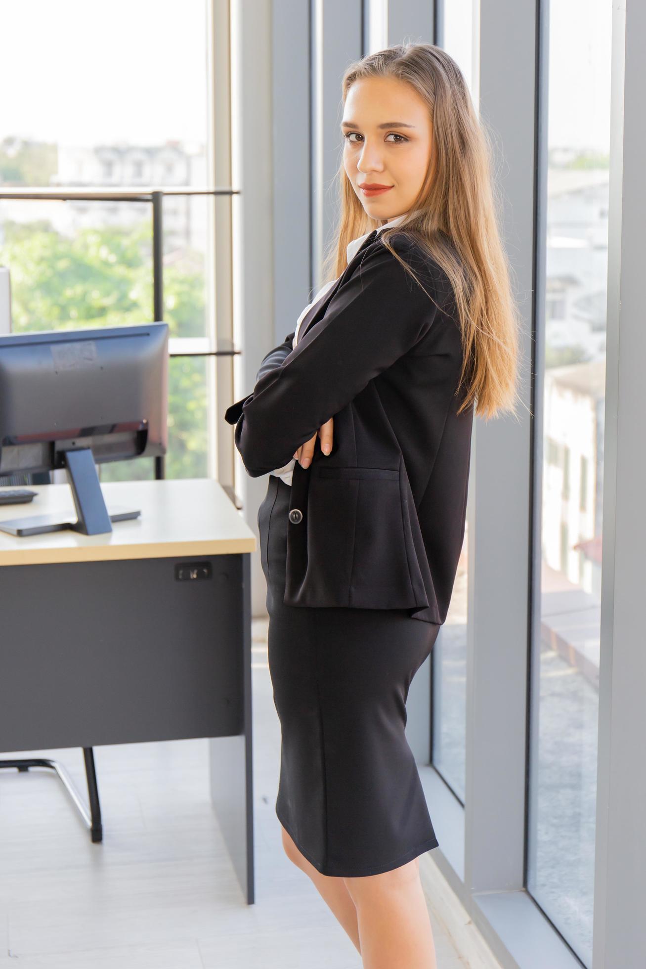 A beautiful young business woman standing next to a glass wall in an office Stock Free