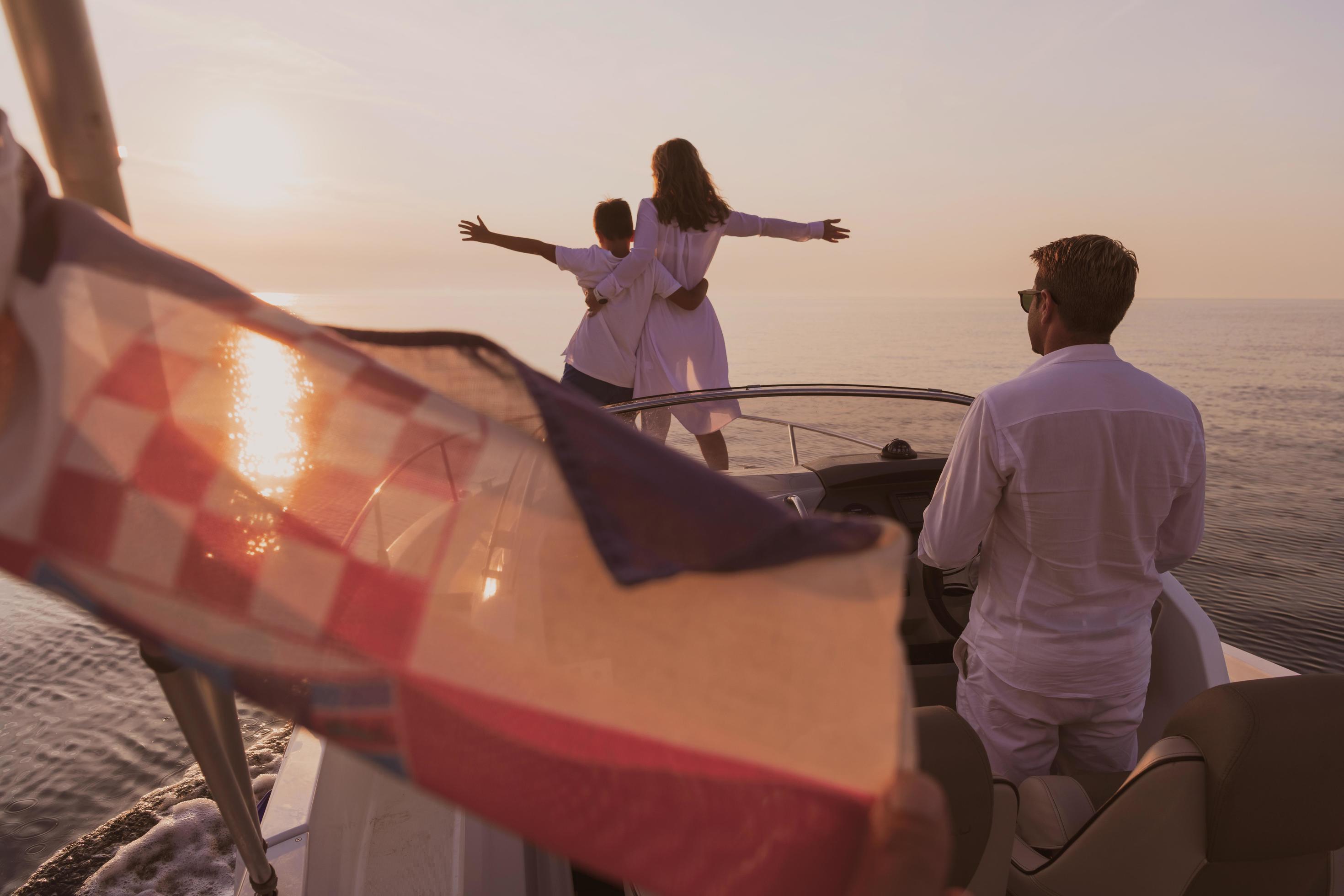 A senior couple in casual outfits with their son enjoy while riding a boat at sea at sunset. The concept of a happy family. Selective focus Stock Free