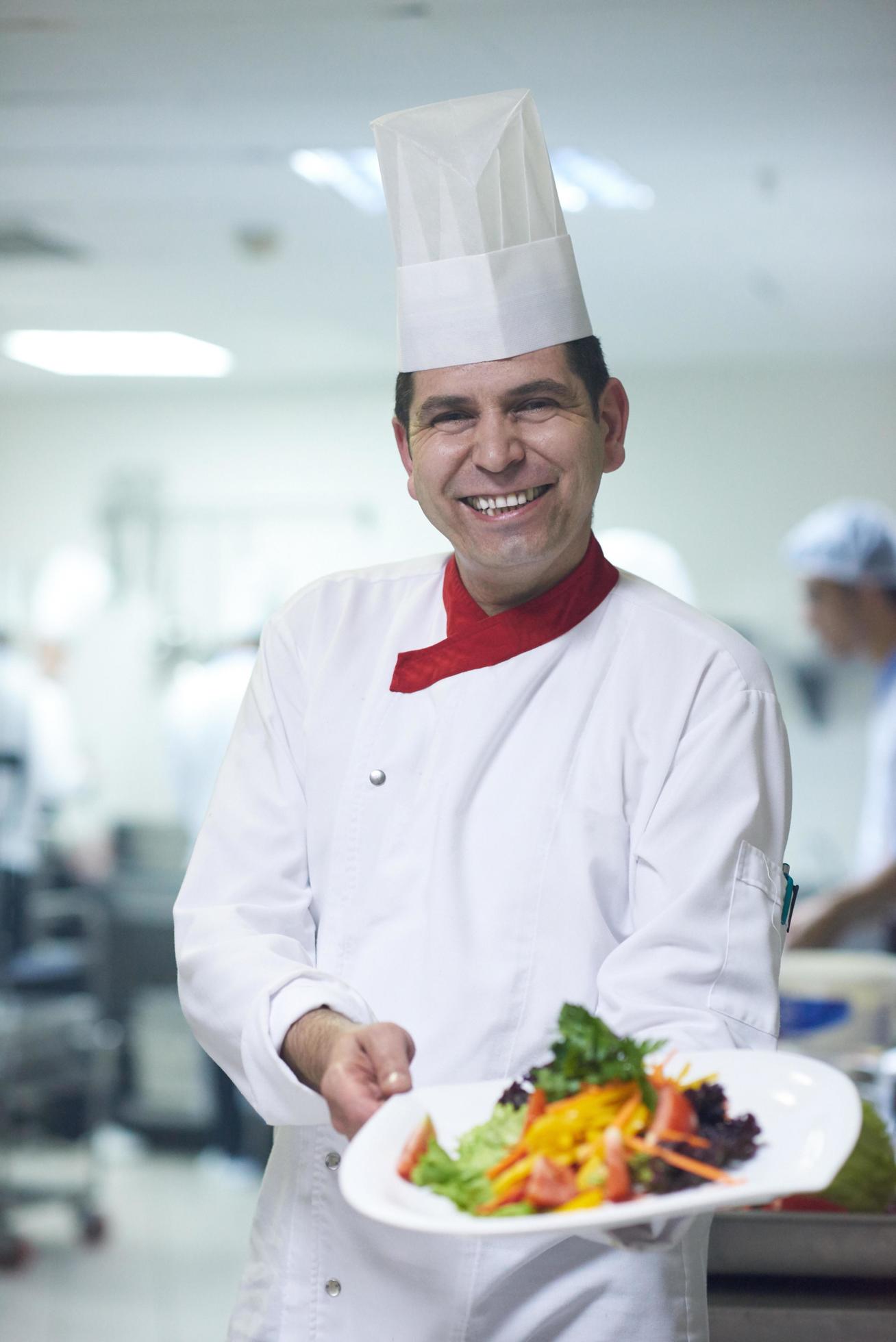 chef in hotel kitchen preparing and decorating food Stock Free