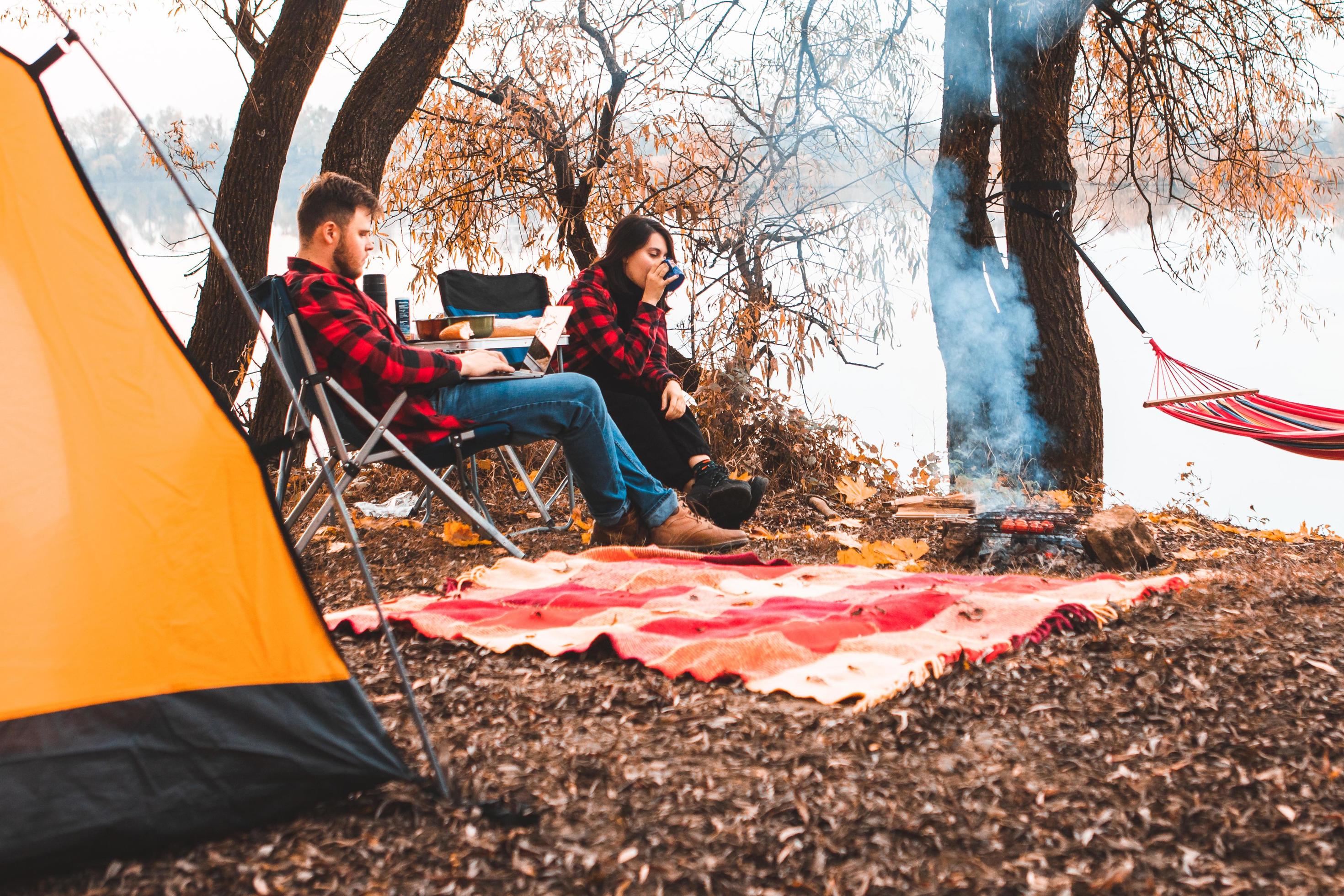 Smiling happy couple resting near fire cooking food Stock Free