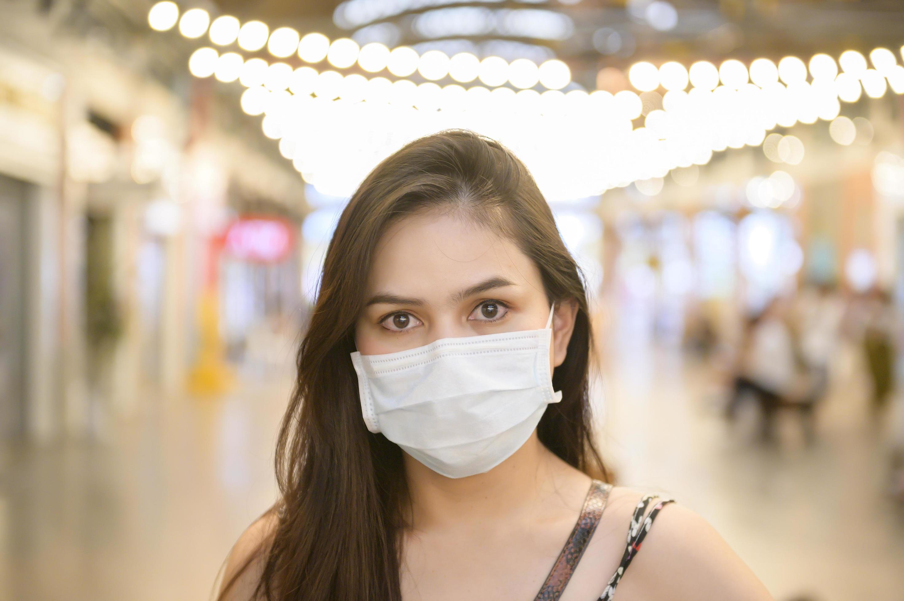 A young Asian woman is wearing protective mask shopping in shopping center, Coronavirus protection,New normal lifestyle concept Stock Free