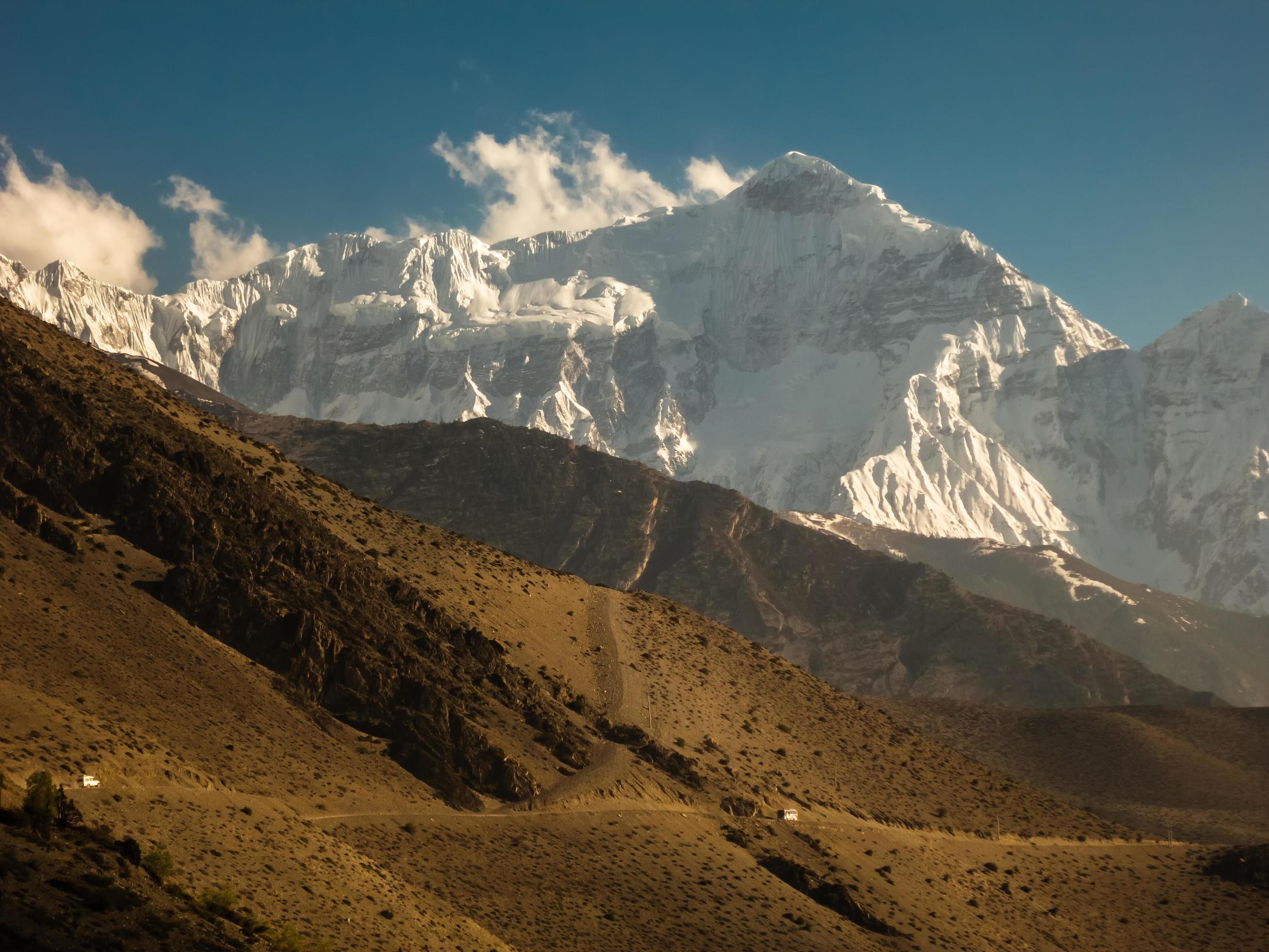 The Nilgiri North mountain towering over the sandy hills surrounding the village of Kagbeni on the Annapurna Circuit trekking trail in Nepal. Stock Free