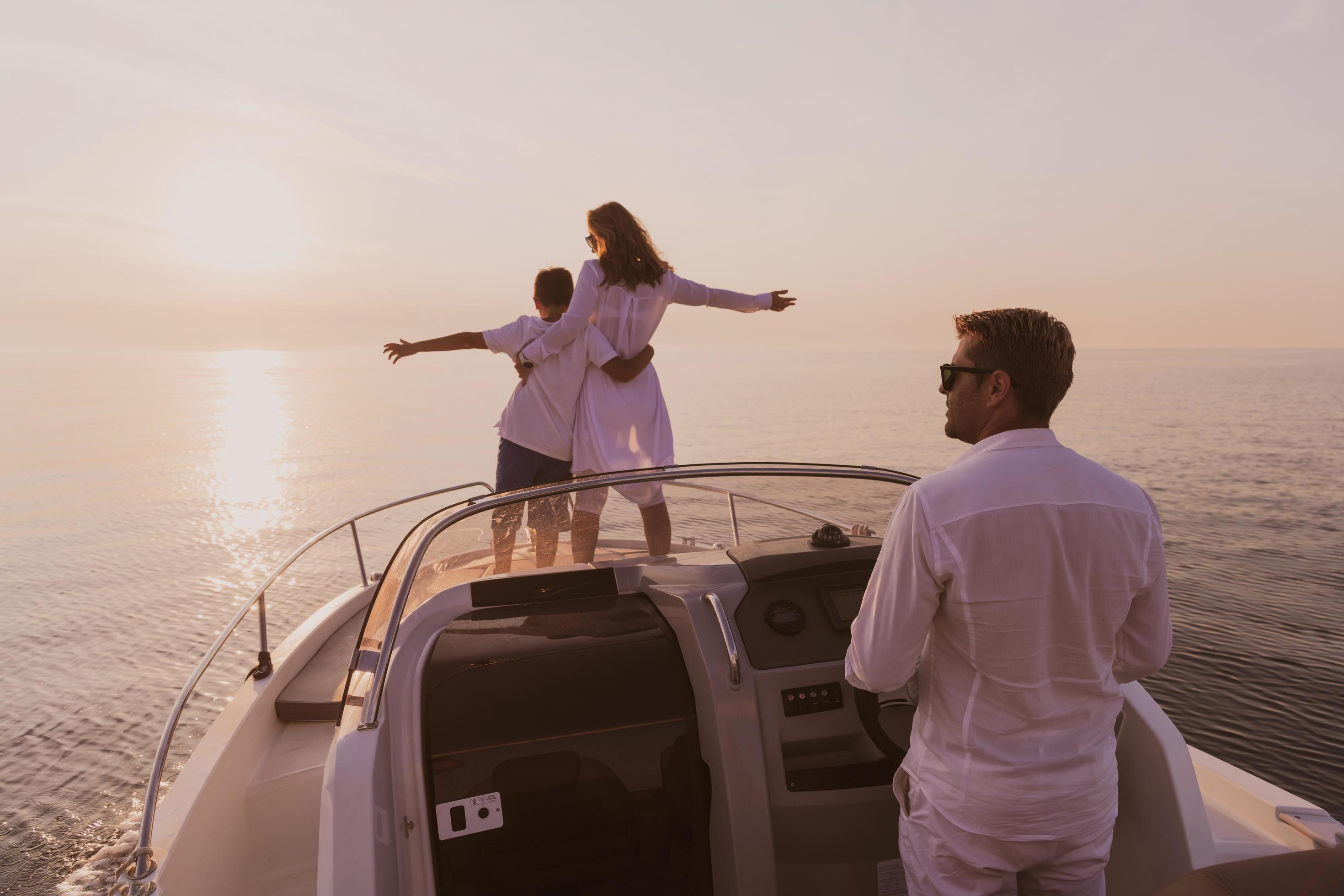 A senior couple in casual outfits with their son enjoy while riding a boat at sea at sunset. The concept of a happy family. Selective focus Stock Free