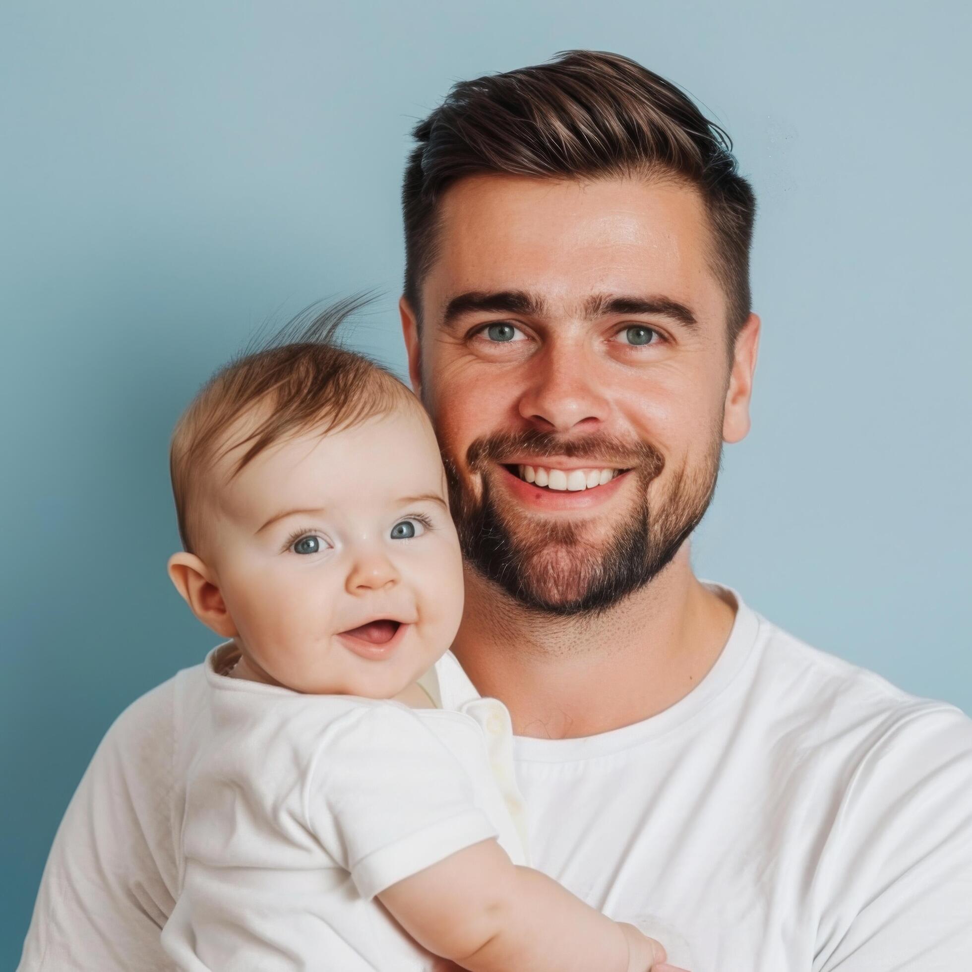 Smiling father holding a happy baby against a blue background, suitable for family or parenting concepts Stock Free