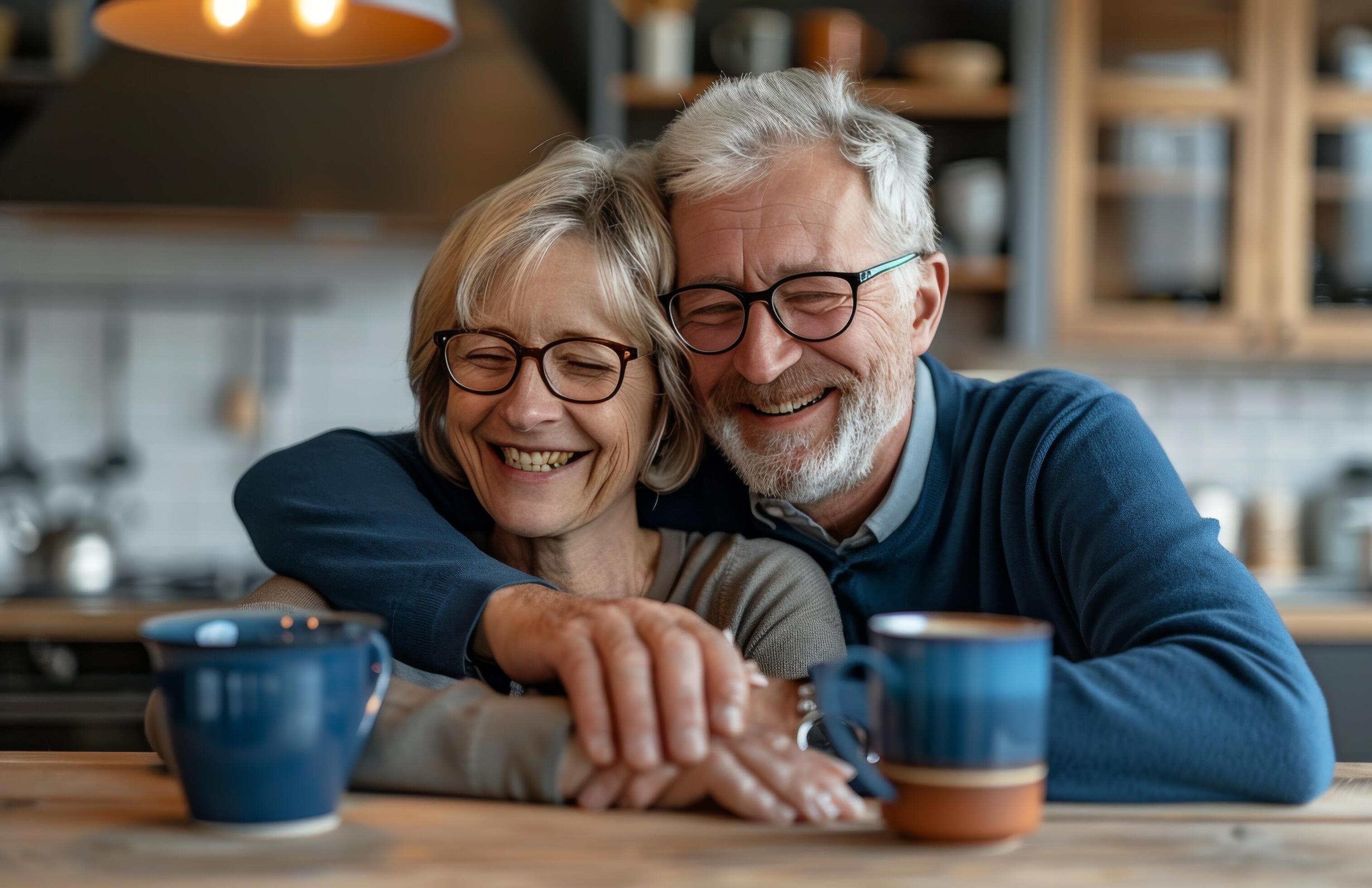 Smiling Senior Couple Enjoying Coffee Together In Their Home Kitchen Stock Free