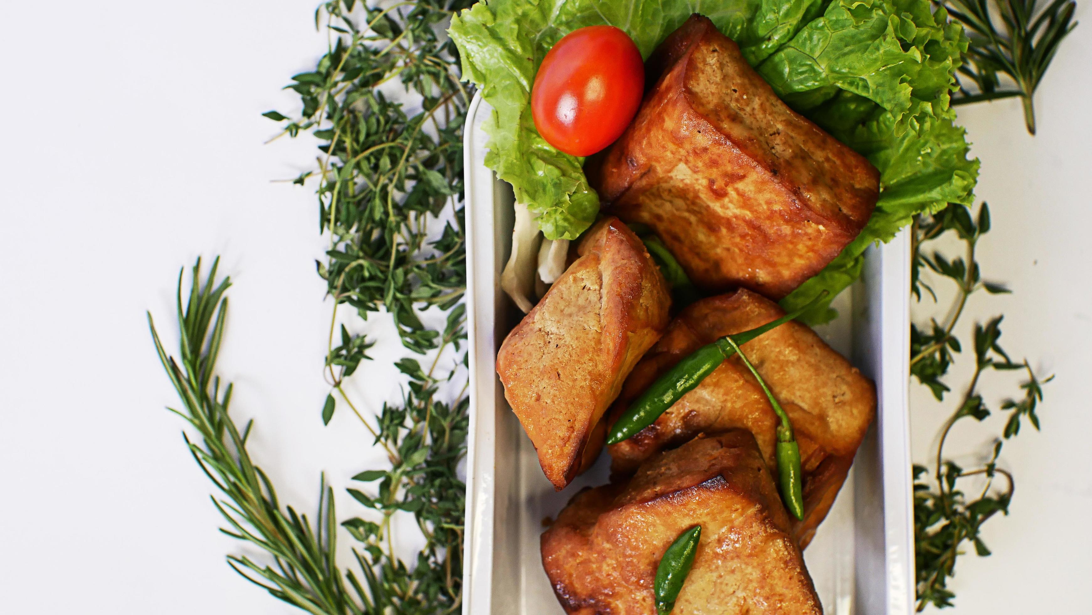 Fried tofu, small tomatoes and green chilies along with lettuce in one aluminum container, Indonesian street food on a white background Stock Free