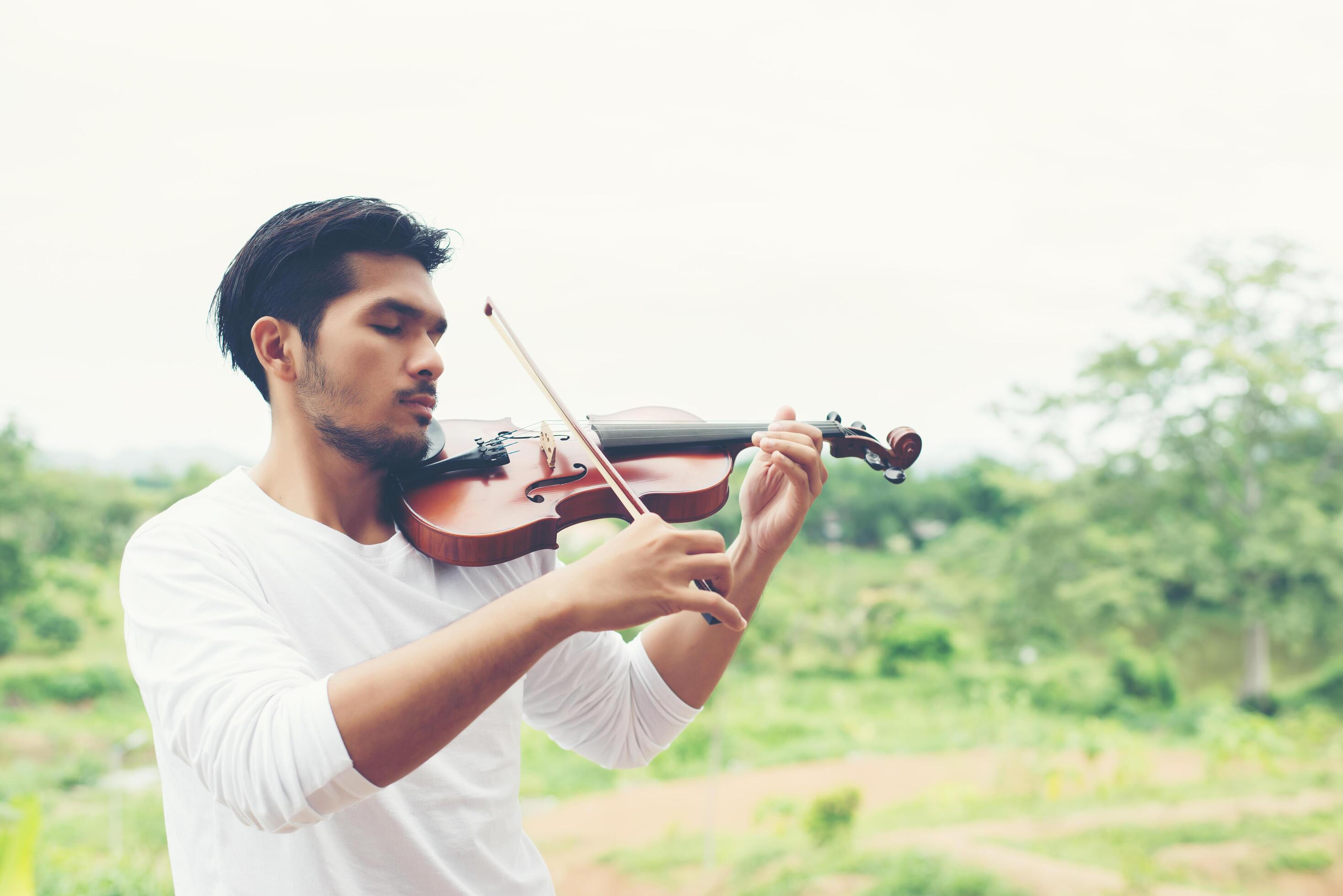 Young hipster musician man play violin in the nature outdoor lifestyle behind mountain. Stock Free