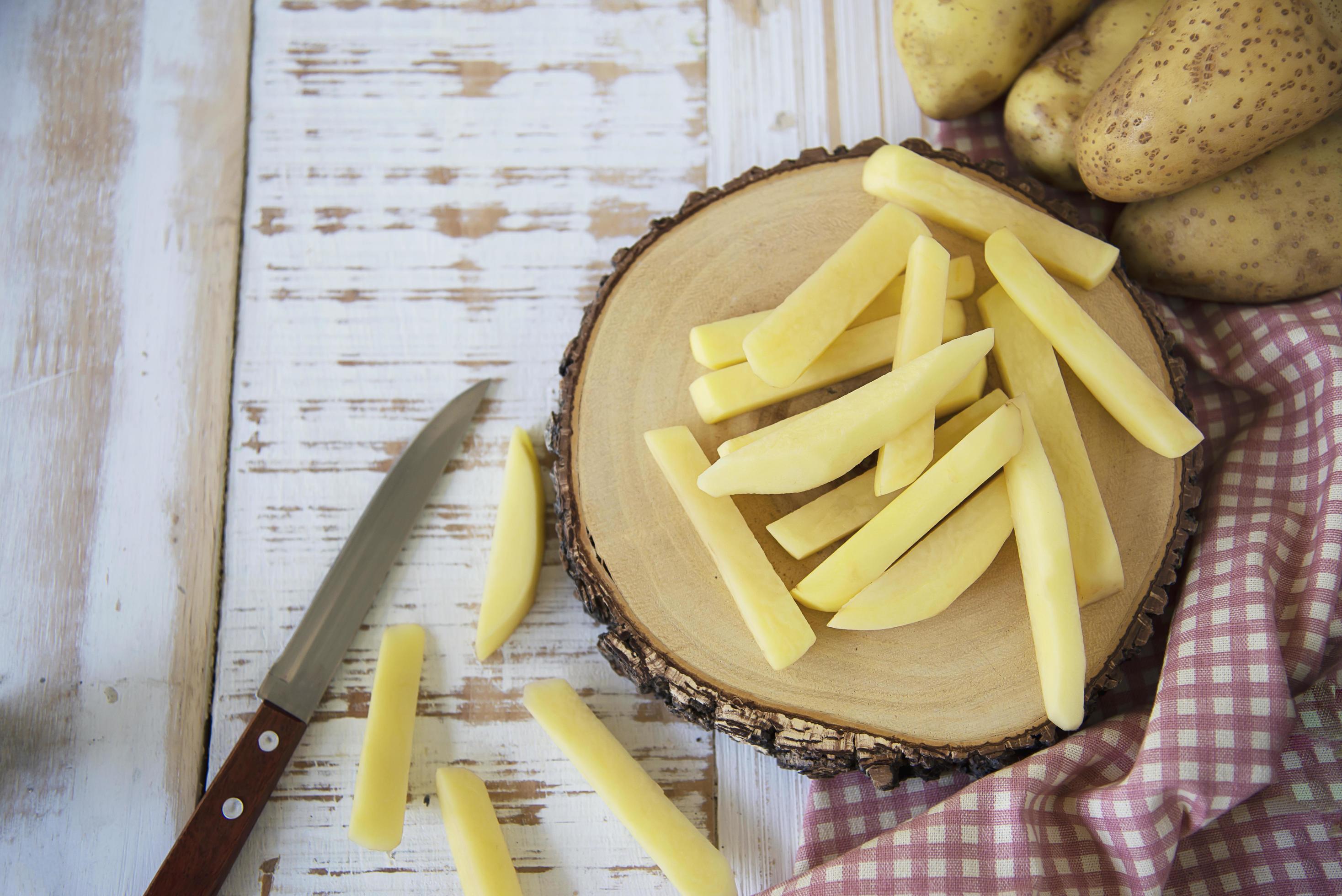 Sliced potato stick ready for making French fries – traditional food preparation concept Stock Free