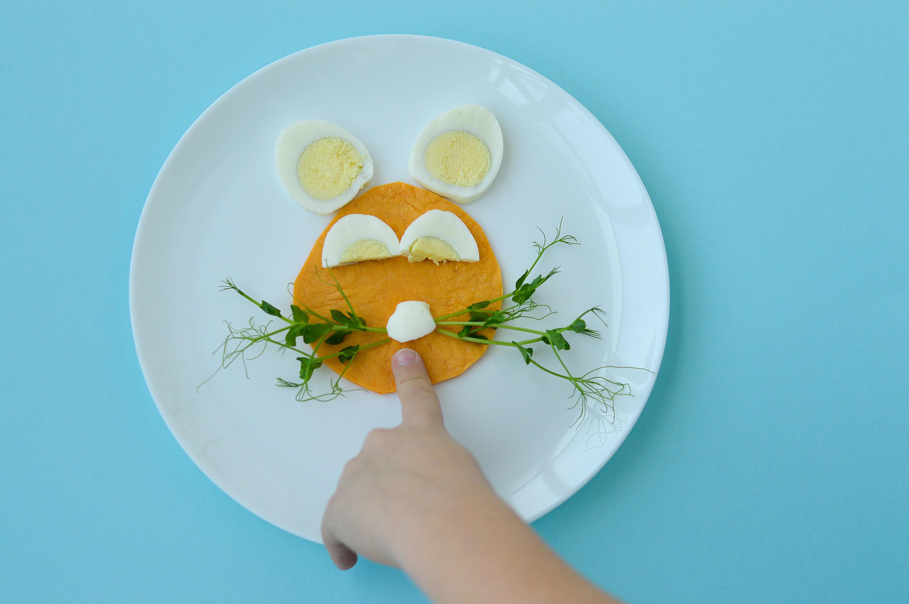 Easter breakfast bunny rabbit lunch plate, fun food art idea for kids of boiled egg, pancake and young greens. Top view. Stock Free