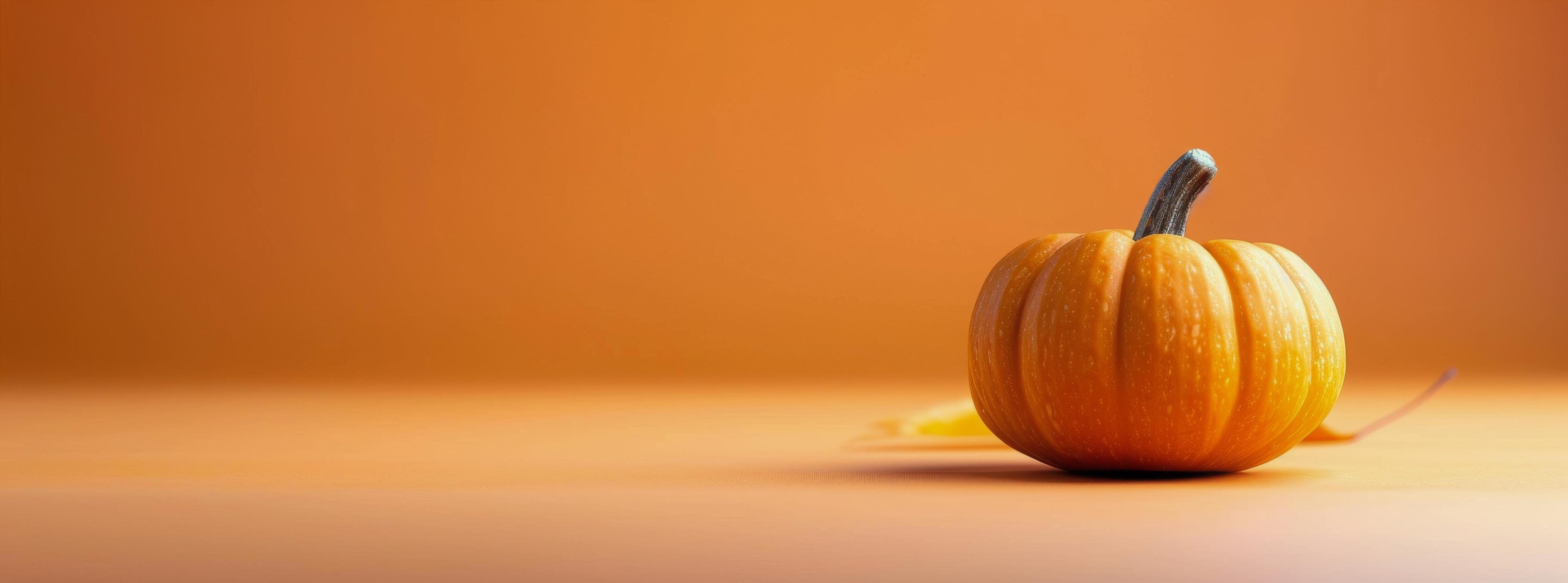 Vibrant Orange Pumpkin on White Surface Against Bright Orange Background in Autumn Stock Free