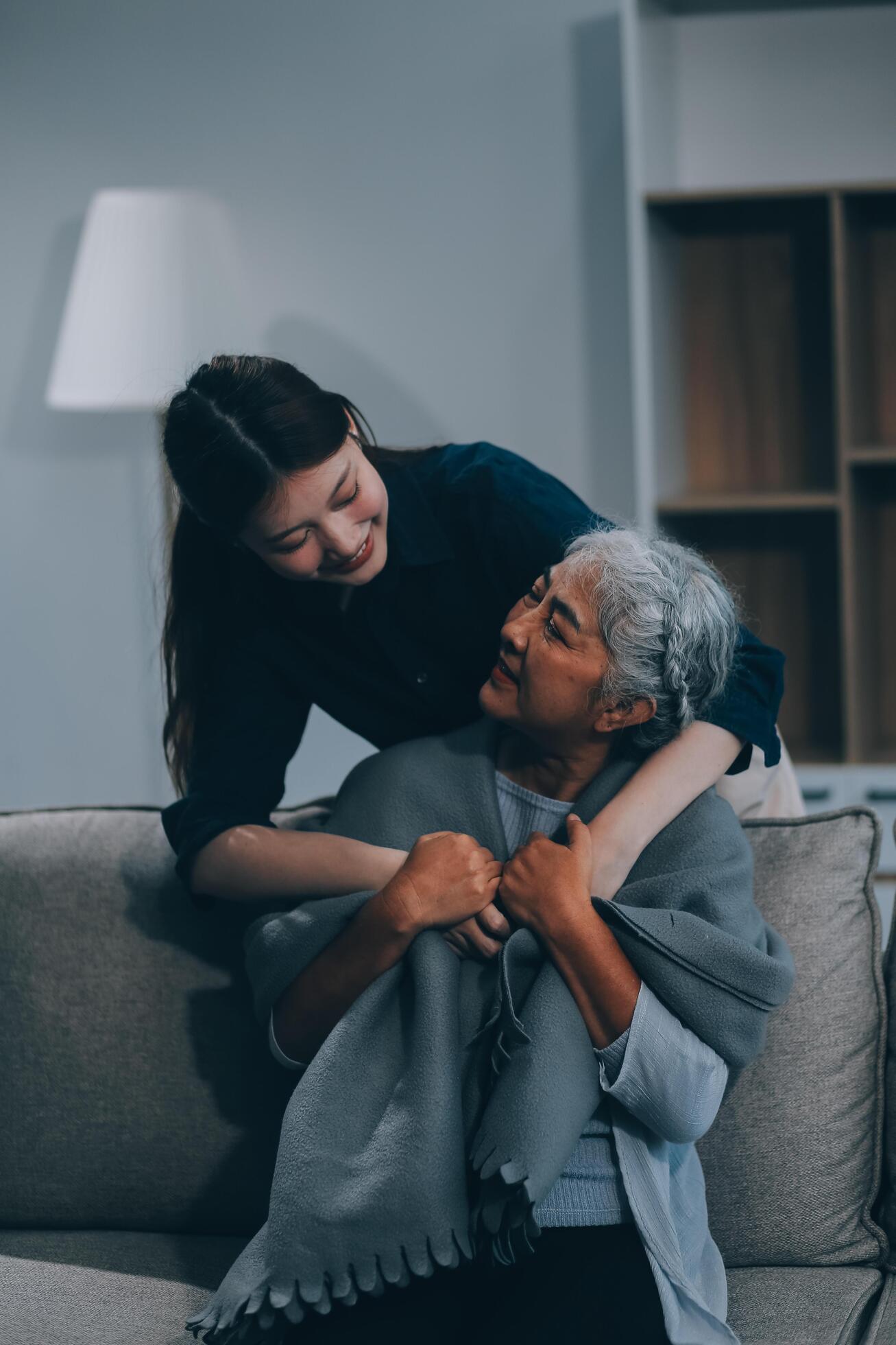 happy family Granddaughter takes care of her grandmother with warm cloths sitting on the sofa. Stock Free