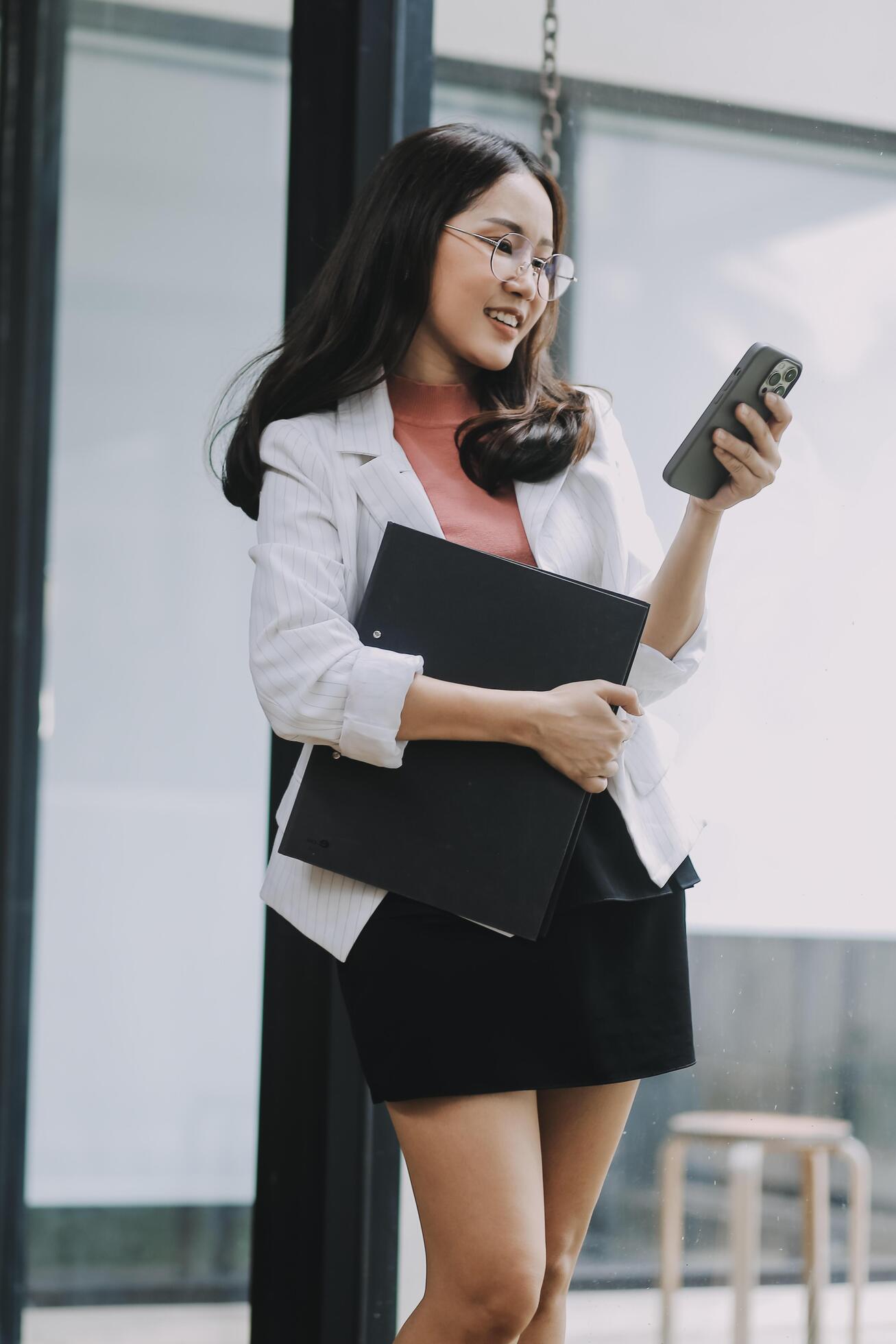 Portrait of a happy Asian businesswoman using mobile phone indoor, Asian businesswoman working in modern office. Stock Free