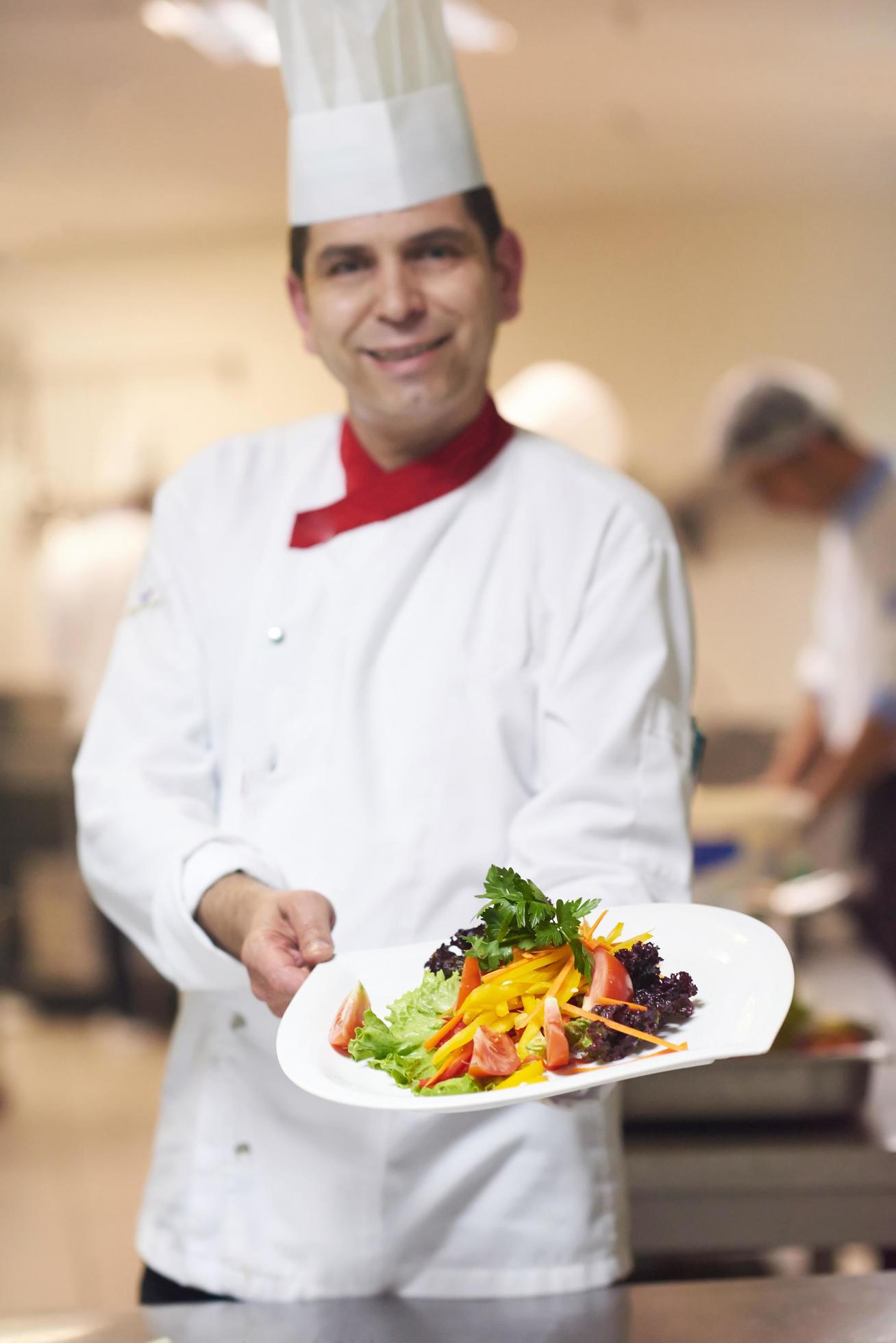 chef in hotel kitchen preparing and decorating food Stock Free