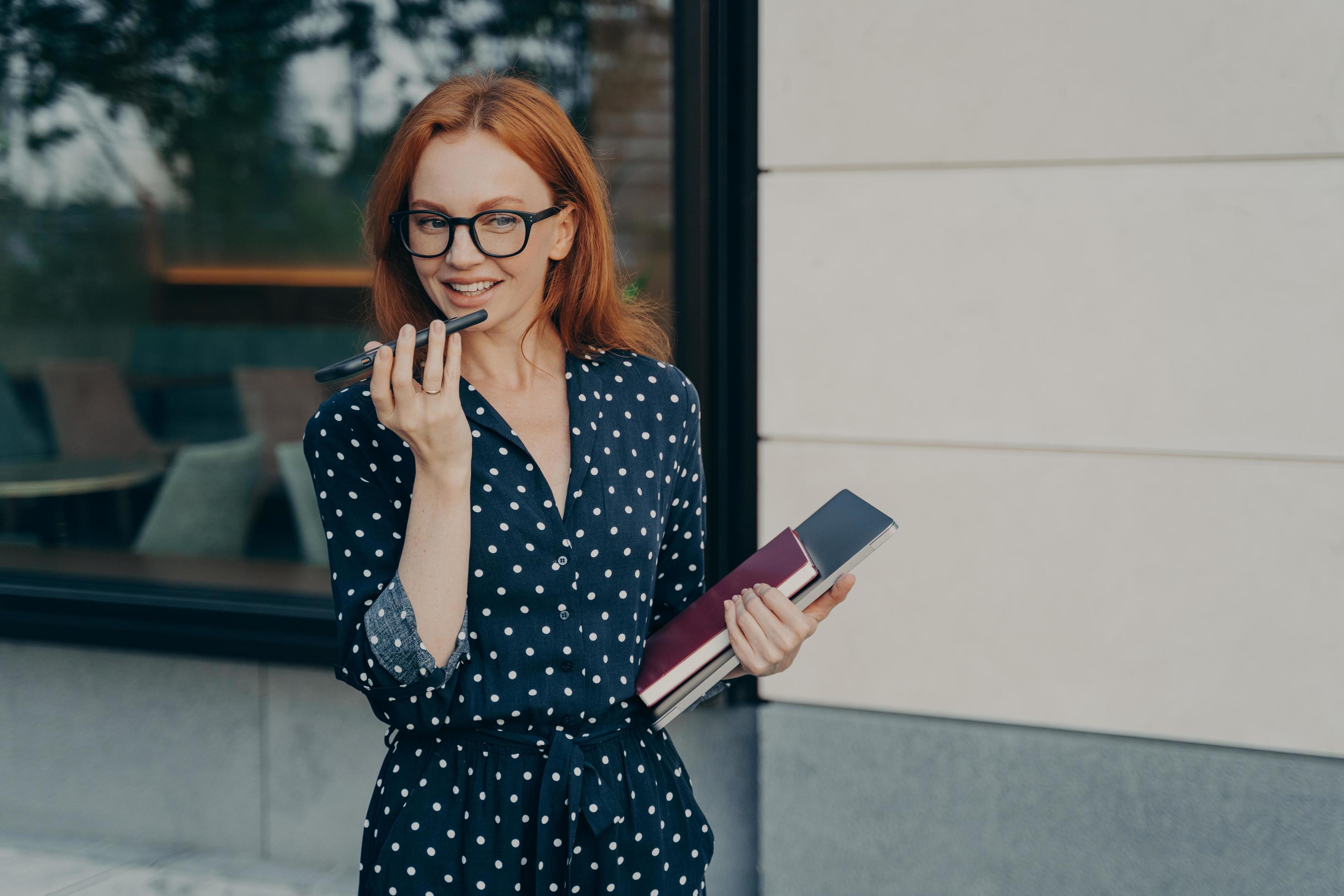 
									Beautiful smiling business woman using speakerphone or virtual voice assistant on mobile phone Stock Free