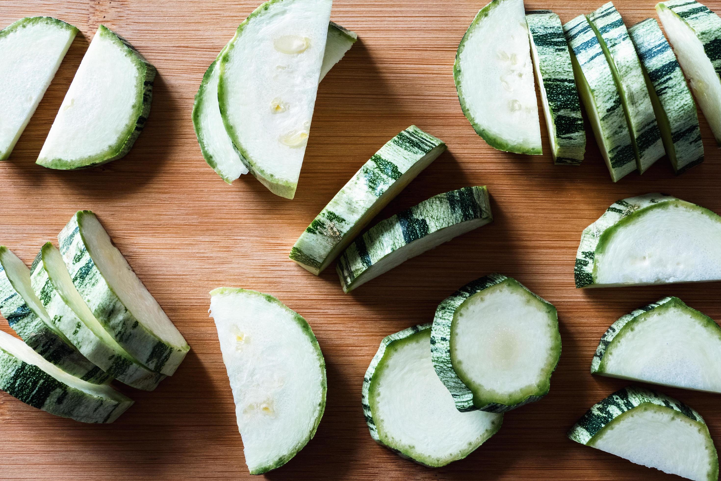 Closeup of sliced zucchini on wooden cutting board, food flat lay Stock Free