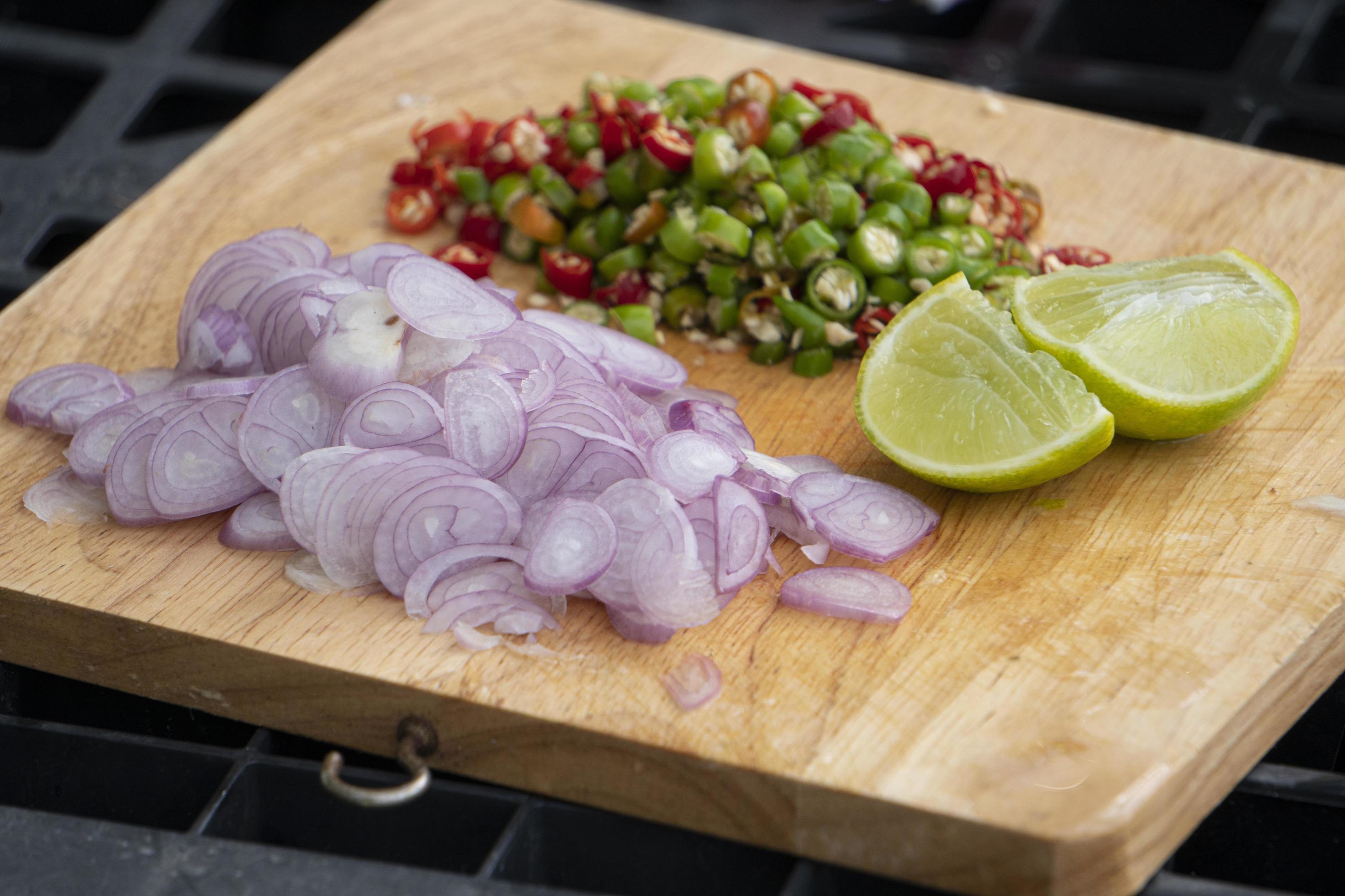 Side dishes of Red onion, fresh chili, lime are sliced on a wooden chopping board. Food set for Thai kitchen. Stock Free