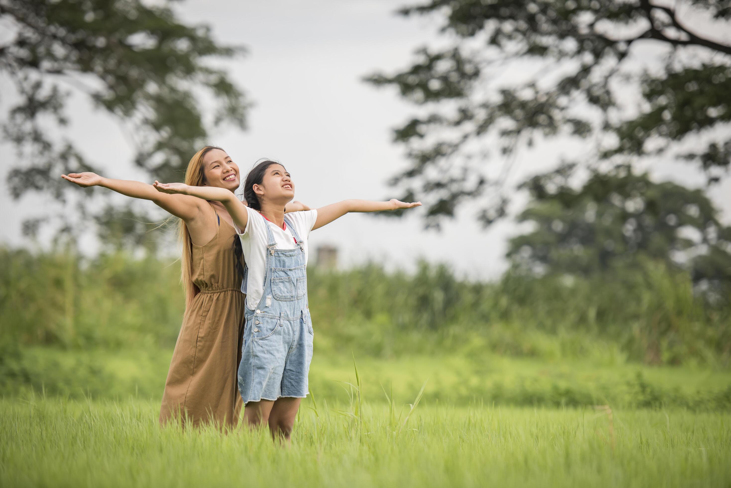 Mother and daughter standing happy in grass field Stock Free