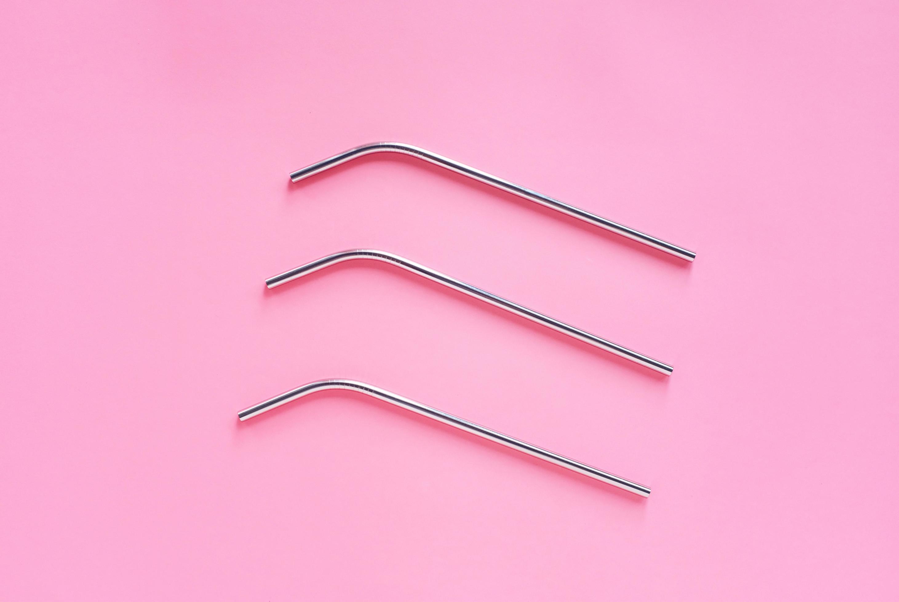 Flat lay of metallic stainless straws for drink on bright pink background, sustainable lifestyle and zero waste concept Stock Free