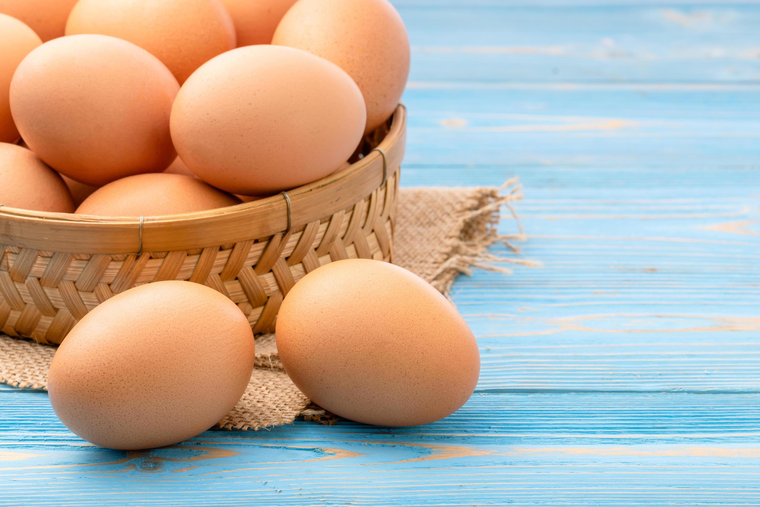 Fresh eggs in bamboo basket on blue wooden background. for food concept Stock Free