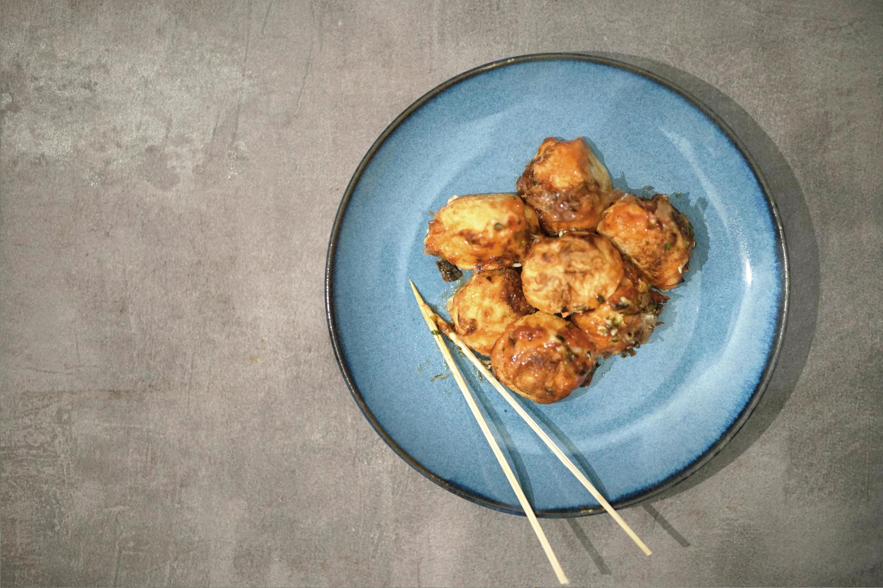 traditional japanese food, takoyaki with sauce on a blue plate Stock Free