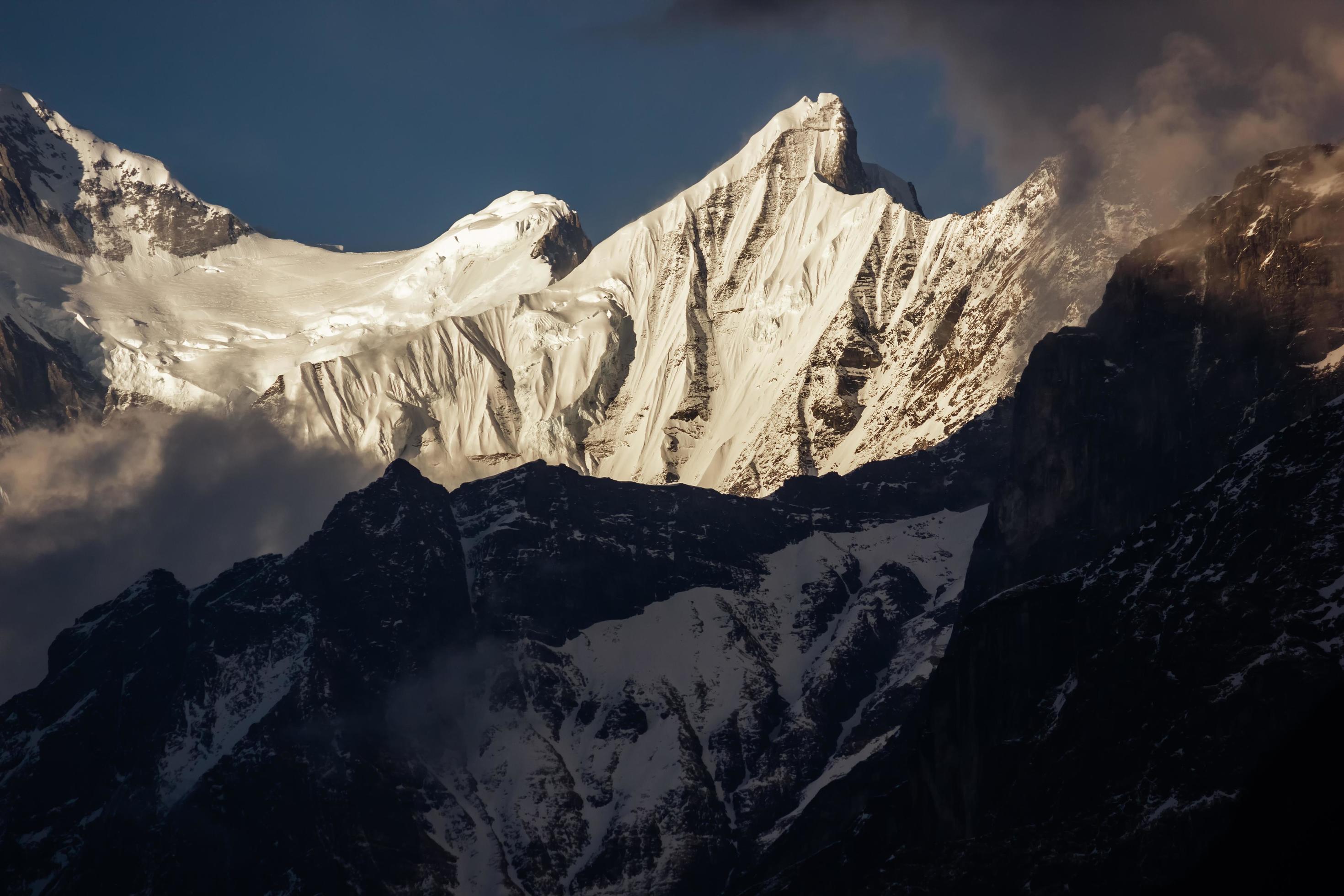 Sunlight hits a peak of the Annapurna range on the Annapurna Base camp trail in the Nepal Himalayas. Stock Free